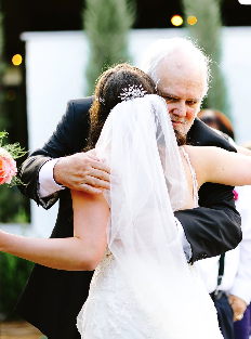 A bride hugging an elderly man at a wedding reception.