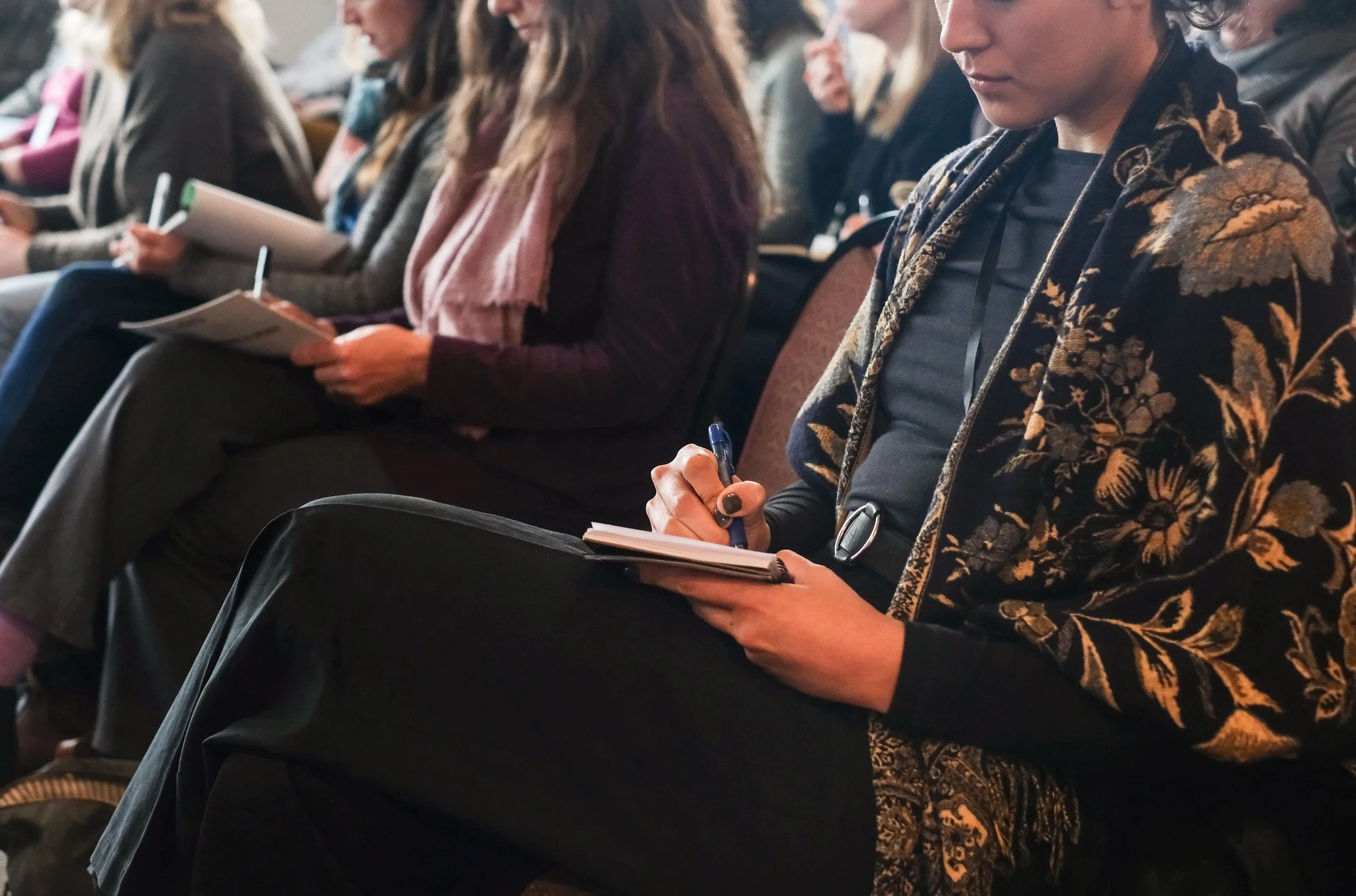 Workshop attendees write in notebooks during a session.