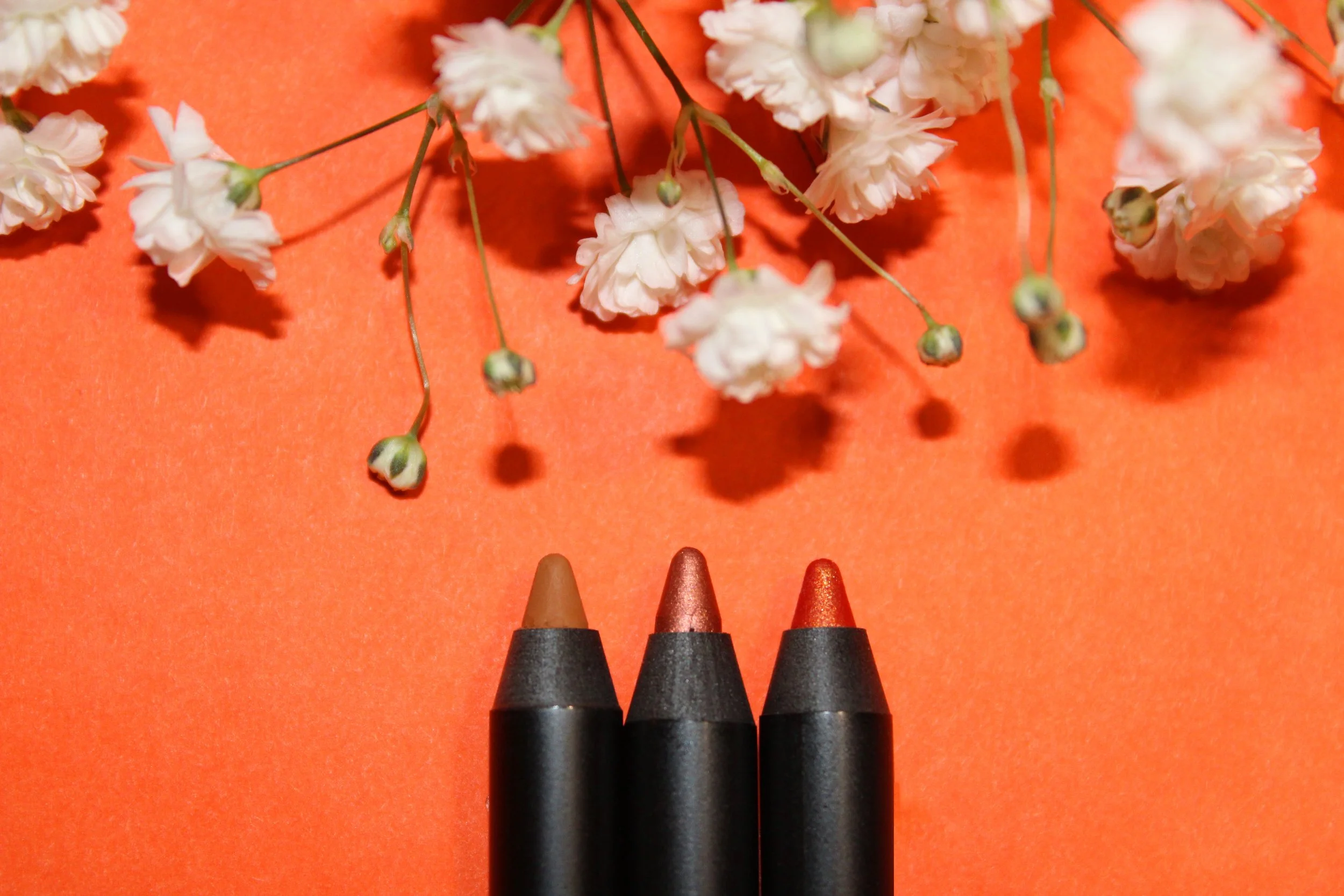 3 eyeliners on orange w flowers.jpg