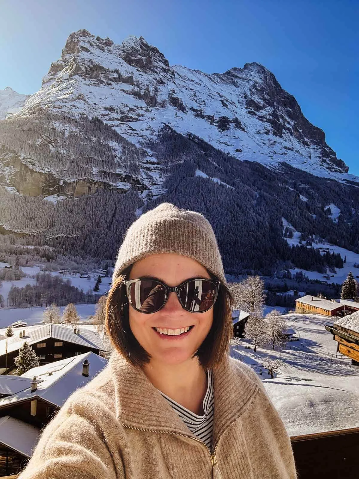 Eiger, Grindelwald backdrop with Kristin Reinhard standing in sunshine on a winter day in Switzerland.