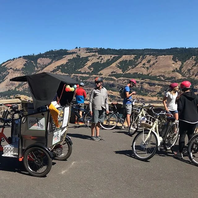 Hood River Pedicab and Sol Rides had our first collaboration this week, and we rolled very well together I must say. Charlie Crocker is a master guide in every sense, sharing his passion for place and people, both present and past, with ease and grace. I sure learned plenty watching him in action. We had a work group from the Nike Beaverton campus out for the day to explore the Gorge and a selection of its wine offerings around the Mosier area. The Twin Tunnels Trail conveyed us from Hood River in epic, scenic style. Kelly of Garnier Vineyards hosted us for the first tasting and we took lunch on their lovely deck. Across the highway we followed our noses to Idiot’s Grace. Trevor took over tour duties here while walking the group through fascinating wine tasting talk, wandering right through the vineyard. The crew, including my rider John with his broken hand, were thoroughly content on the electric-assist cruise back to their cars. Can’t wait to move in the pack again soon! @sol_rides @garniervineyards @idiotsgracewines .
.
.
.
.
#sol_rides #garniervineyards #idiotsgracewines #mosier #columbiariver #columbiarivergorge #traveloregon #pedicab #pedicablife #pedicabs #pedicabdriver #pedicab4life #pedicabvibes #pedicabride #greenliving #radpowerbikes #ssupportlocalbusiness #gorgeowned #localbusiness #peditaxi #peddleassit #visithoodriver #hoodgorge #pnwlife #pnwonderland #columbiagorgous #mthoodterritory #pnwdiscovered #pnwonderland #columbiagorgous #mthoodterritory #pnwdiscovered