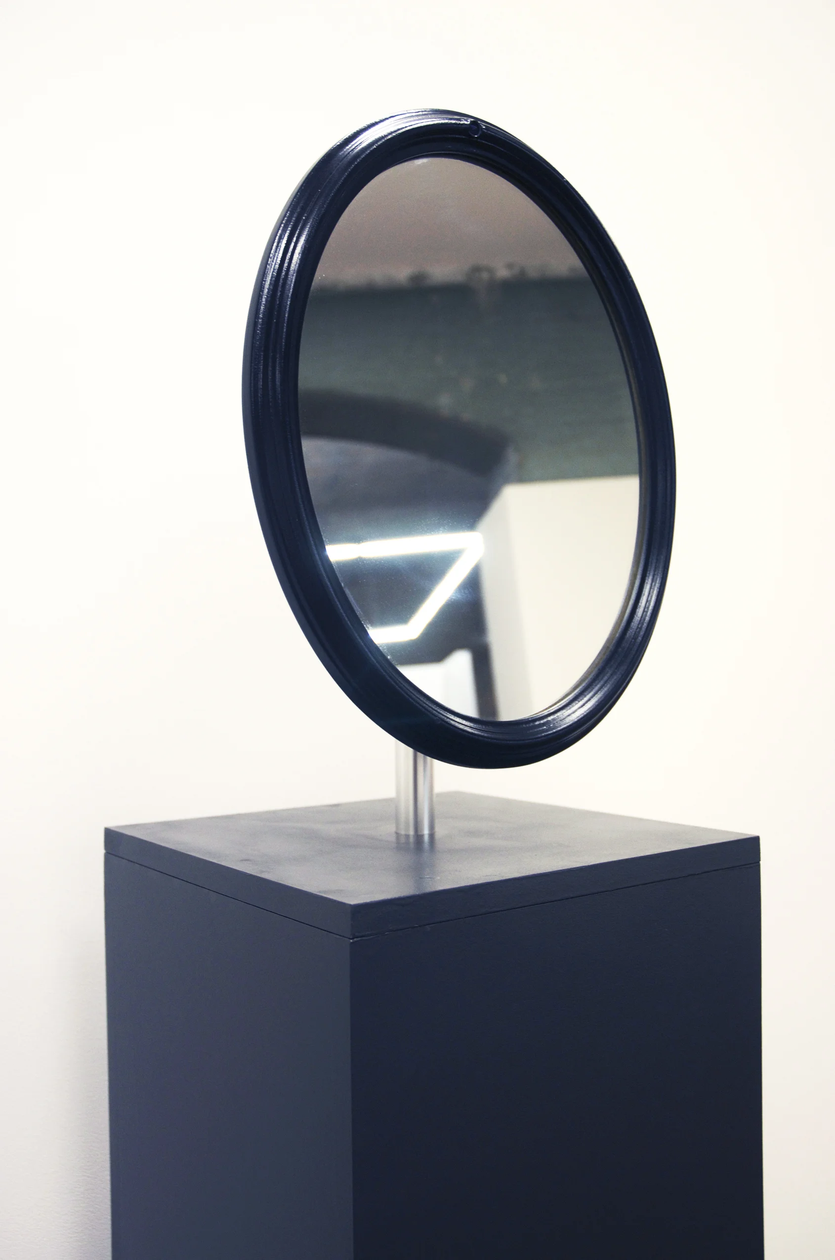 'Are You There' is an interactive work that explores portraiture and its intersection with the notion of place. Consisting of an oval shaped mirror sitting atop an elongated plinth, Are You There is an interactive artwork that was designed to be deliberately mimetic of the human form. The plinth acts as the body, and the mirror acts as a head. The work stands in the gallery space like a humanoid structure, standing still until activated by the proximity of a person attempting to see their reflection. Then, through facial detection software programmed to interact with a micro camera embedded in the mirror frame, the mirror turns away from the face presented to it and denies this reflection. The mirror, by turning away from the person who approaches, is saying ‘no’. This mirror denies us our self-image and appearance.