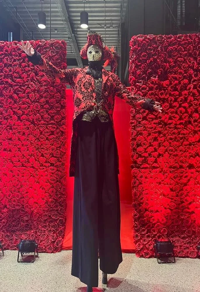 Masquerade stilt walker with a golden mask and feathered cap