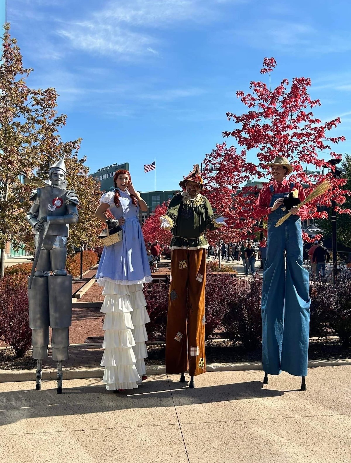 TIn Man stilts, Dorothy stilt walker, Scarecrow, and a Farmer stilt walker pose together