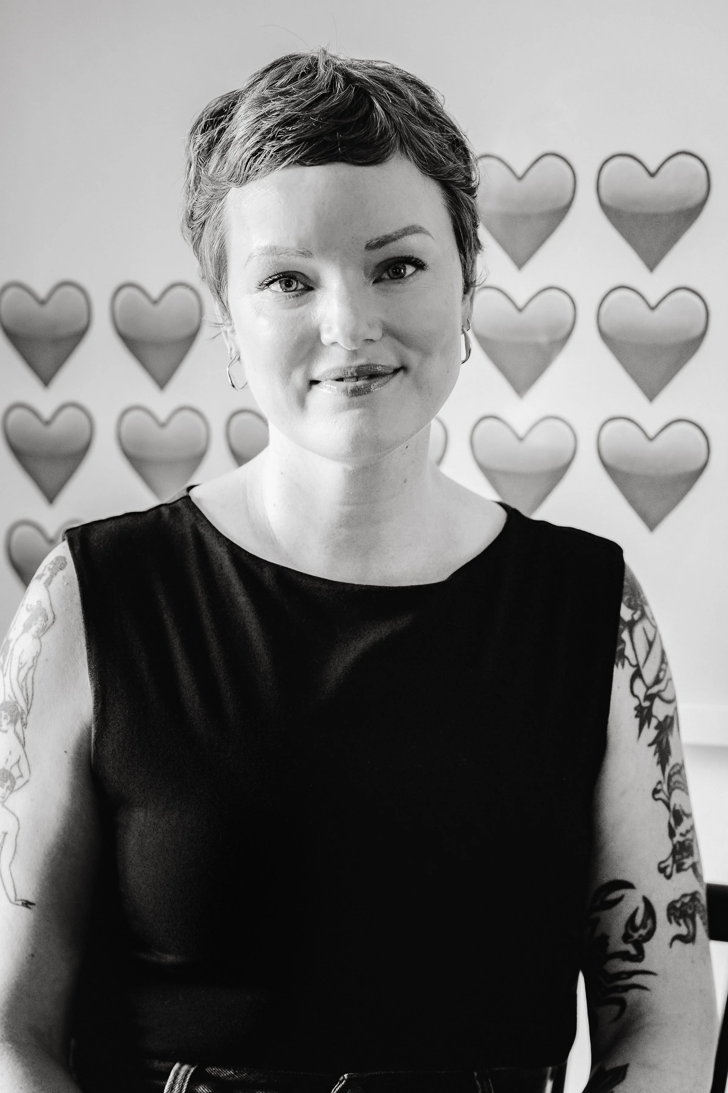 Close up portrait of the author's smiling face with a backdrop of heart emojjis from artwork by Anna Von Mertens from her Love Letters series