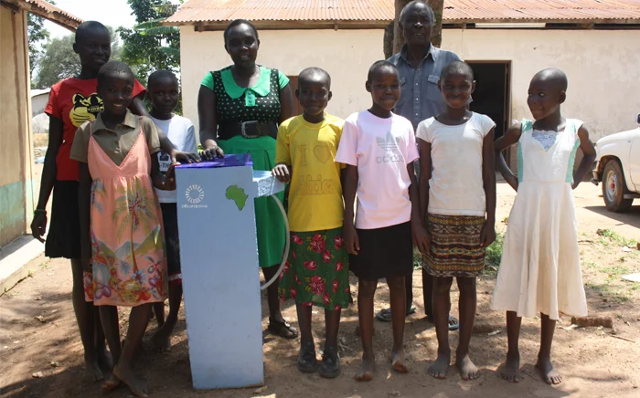 A group of Kenyan school children and their teacher stand with the water filter that is going into their classroom!