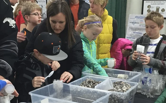 Young Innovators fill their water filters with filtration materials.