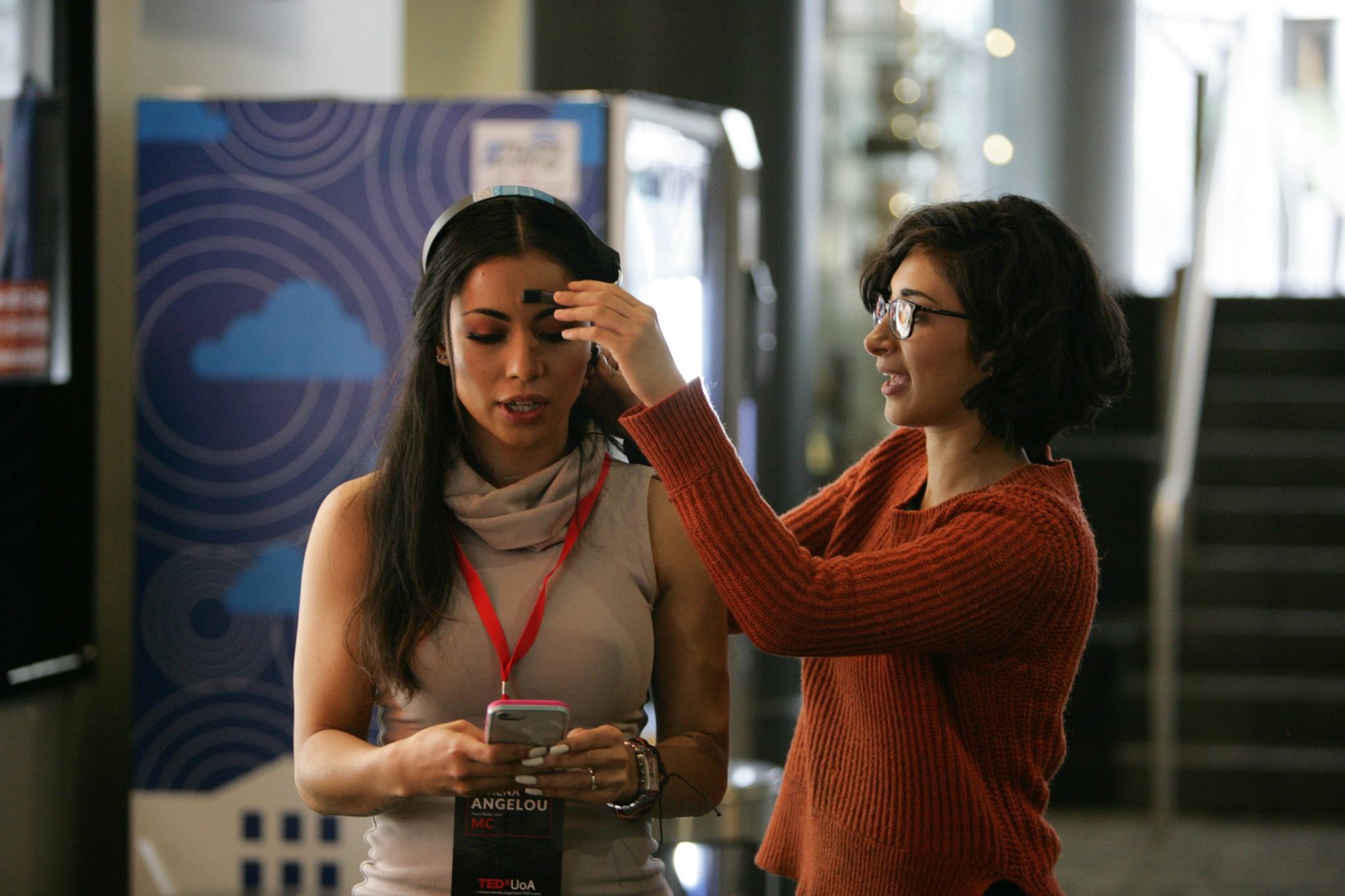 Sarv putting a brain sending device on the MC at TEDx University of Auckland