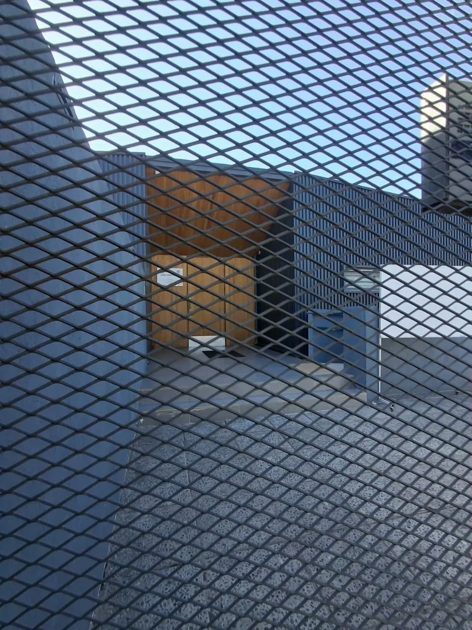 Vista de edificios modernos a través de una reja metálica.