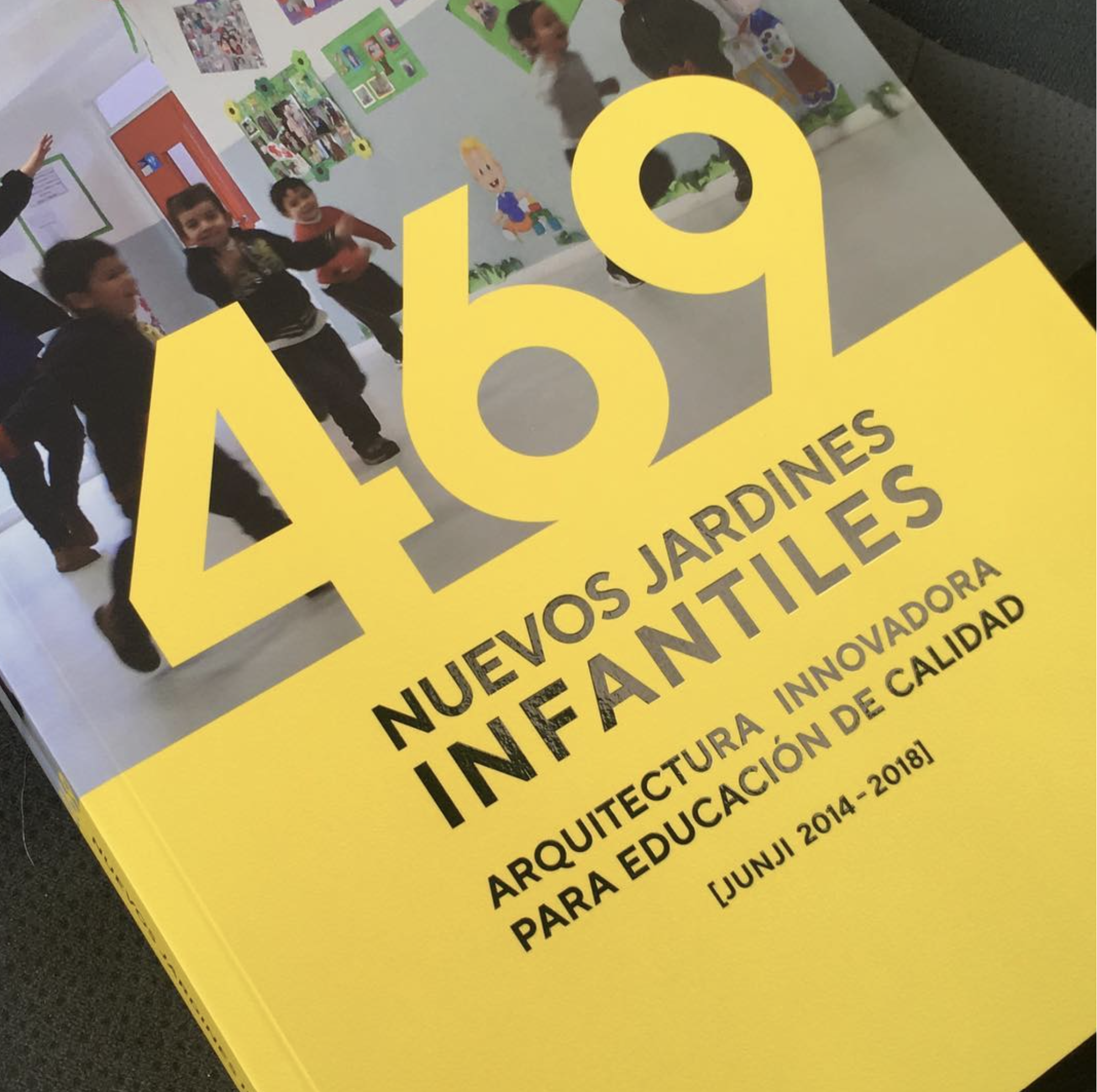 Portada de libro amarillo con texto en español, mostrando un grupo de niños en un aula decorada con dibujos y fotografías, y grandes letras amarillas con el número 49.