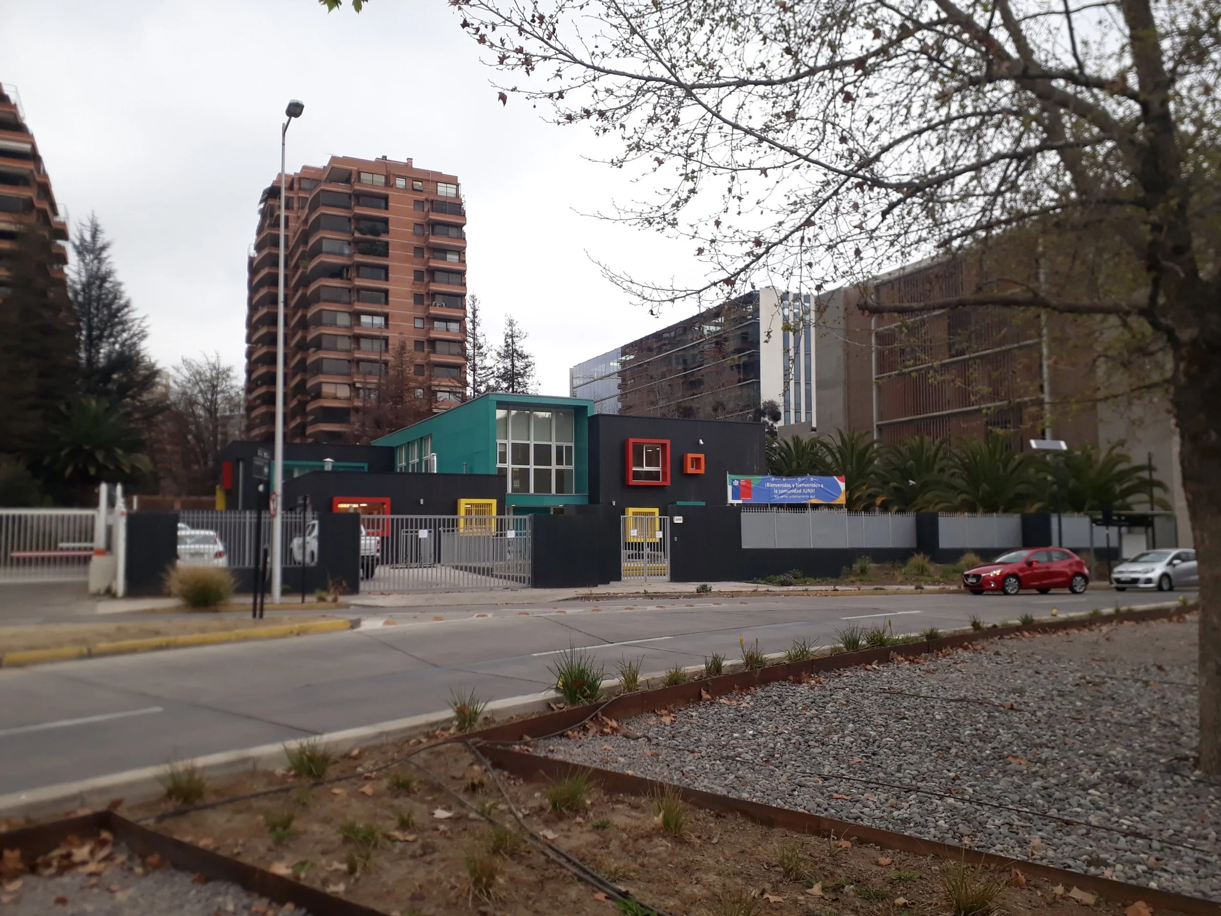Edificio moderno en un entorno urbano, con árboles y calles, en un día nublado.