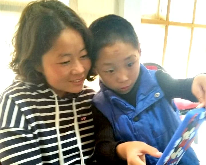Kelsang, home from college, teaches Karsang to take a selfie.