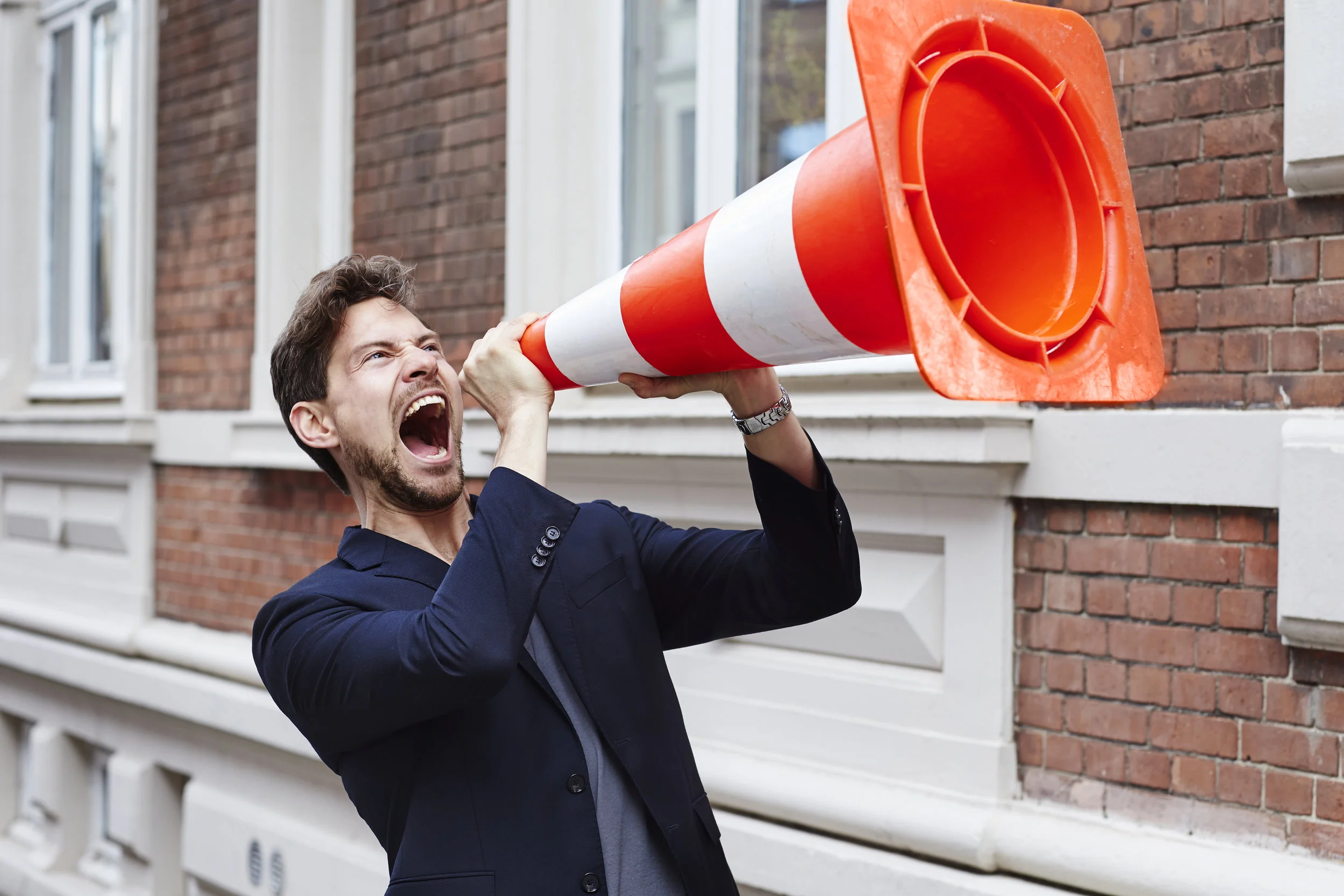 Guy holding traffic cone and making himself heard