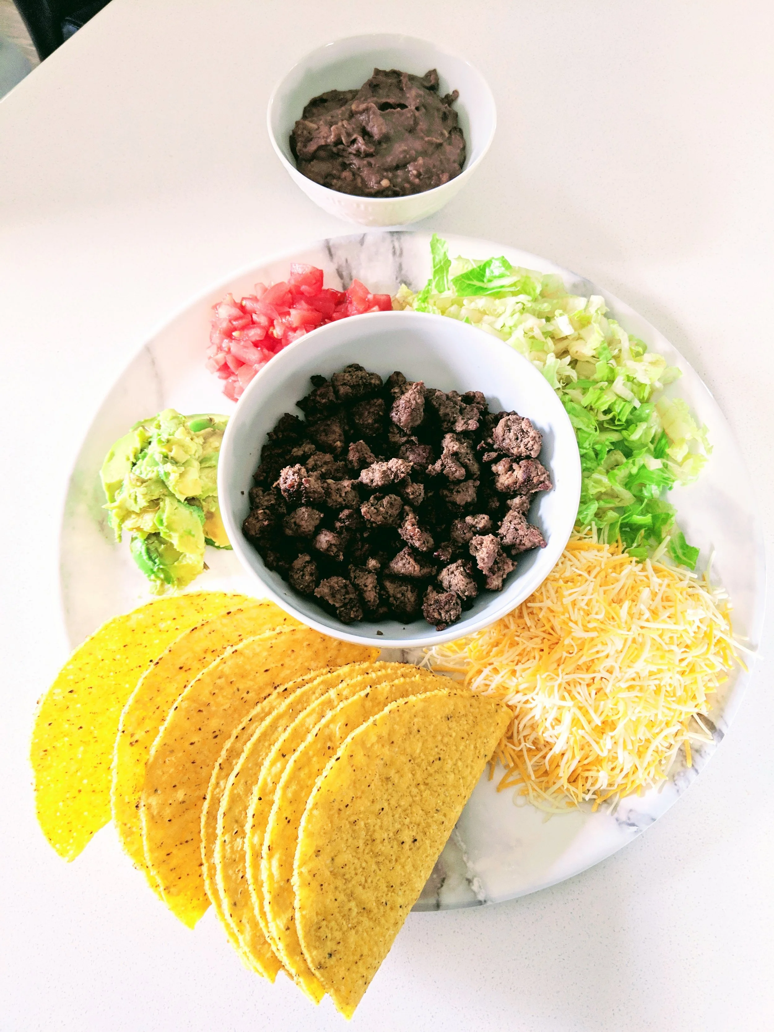 Tacos: Corn taco shells, grinded cheese, lettuce, tomatoes, avocado, ground beef and refried beans.