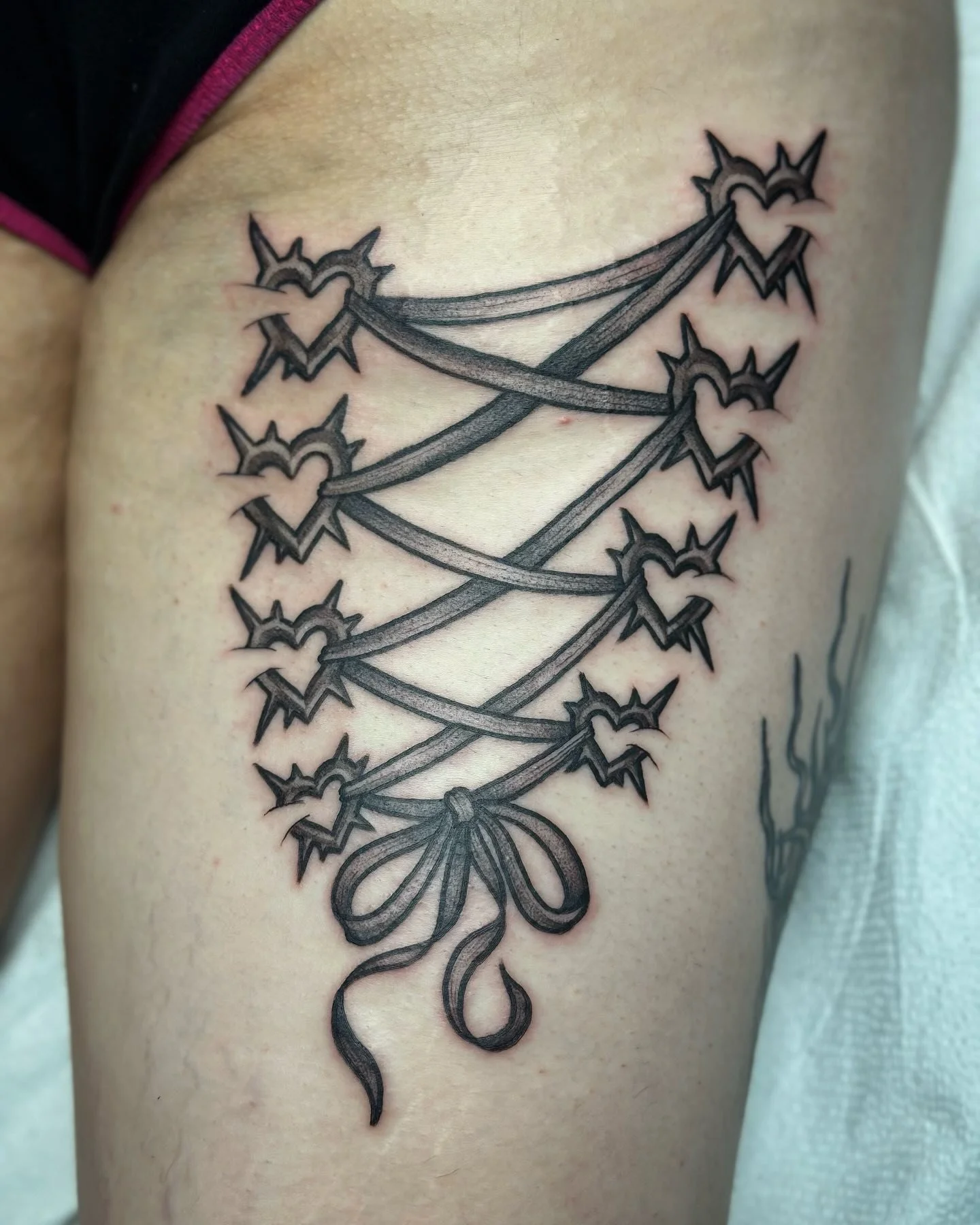 Tattoo of a tied bunch of hearts connected by strings on a person's arm.