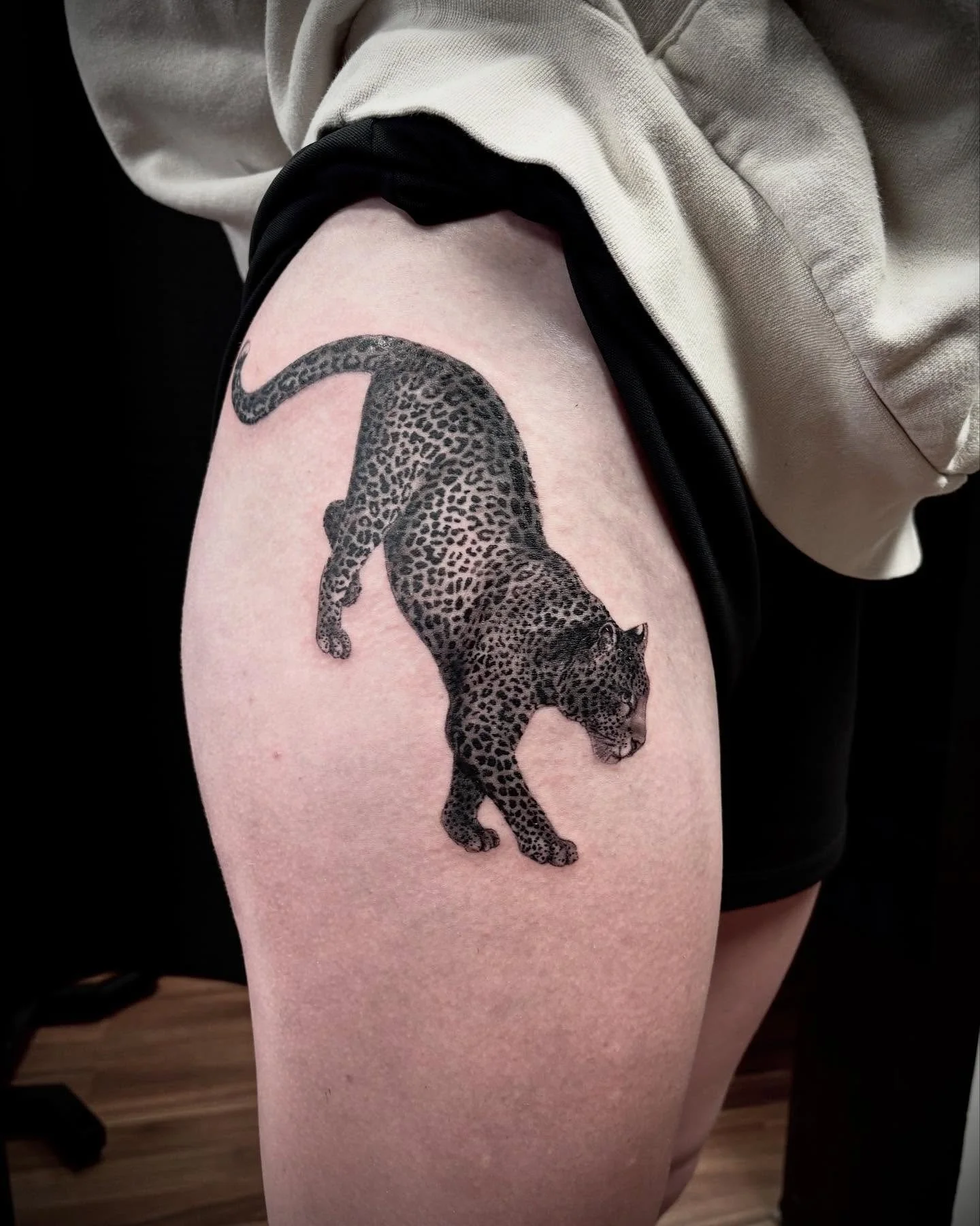 Tattoo of a leopard on a person's upper thigh.