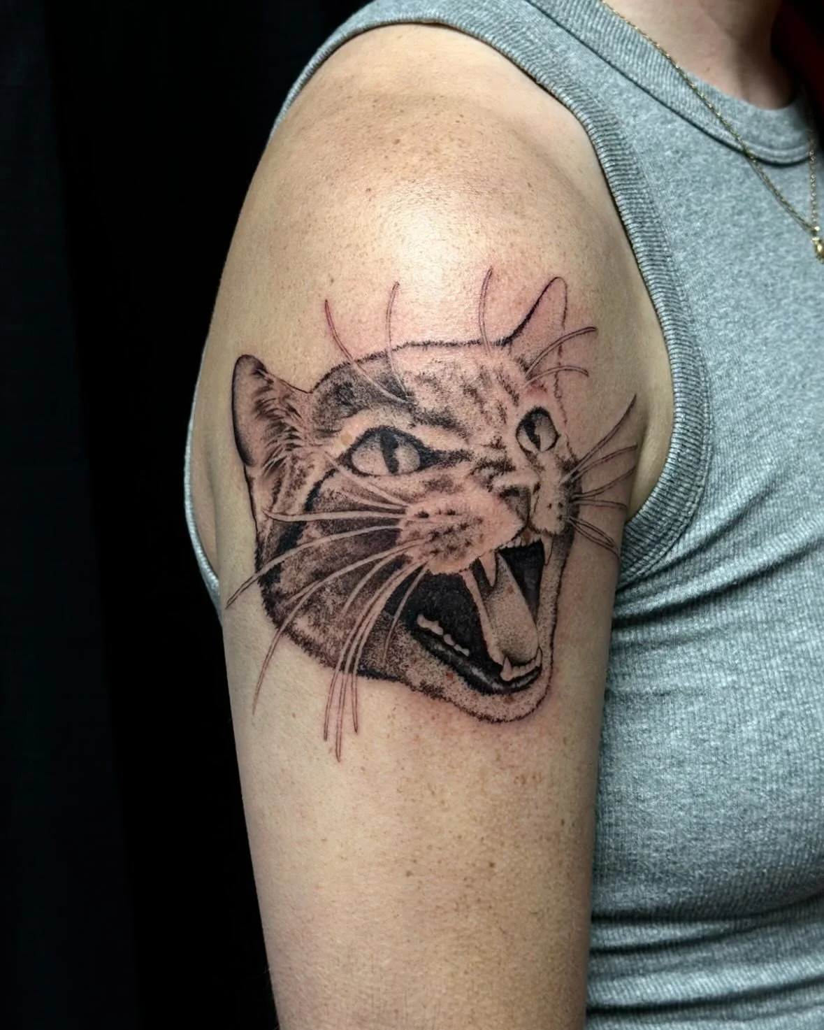 Tattoo of a roaring tiger's face on person's upper arm, featuring detailed shading and line work.