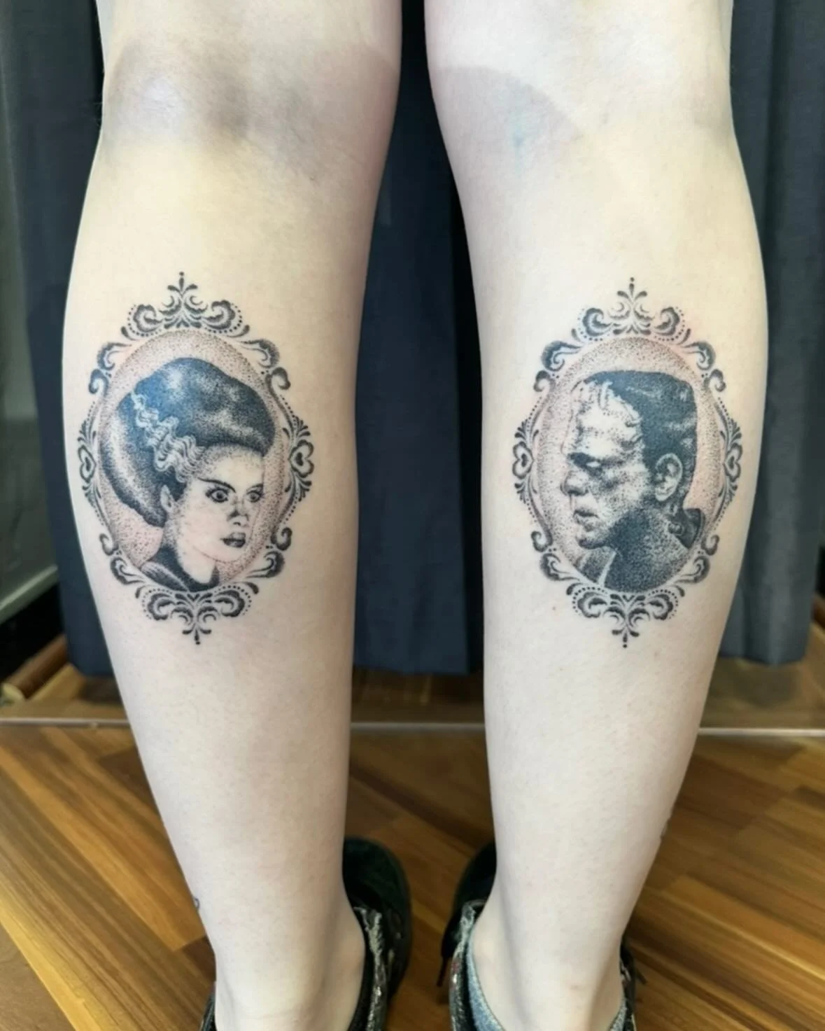 Tattooed portraits of a woman with styled hair on the left thigh and a man with glasses on the right thigh, both framed with ornate borders.