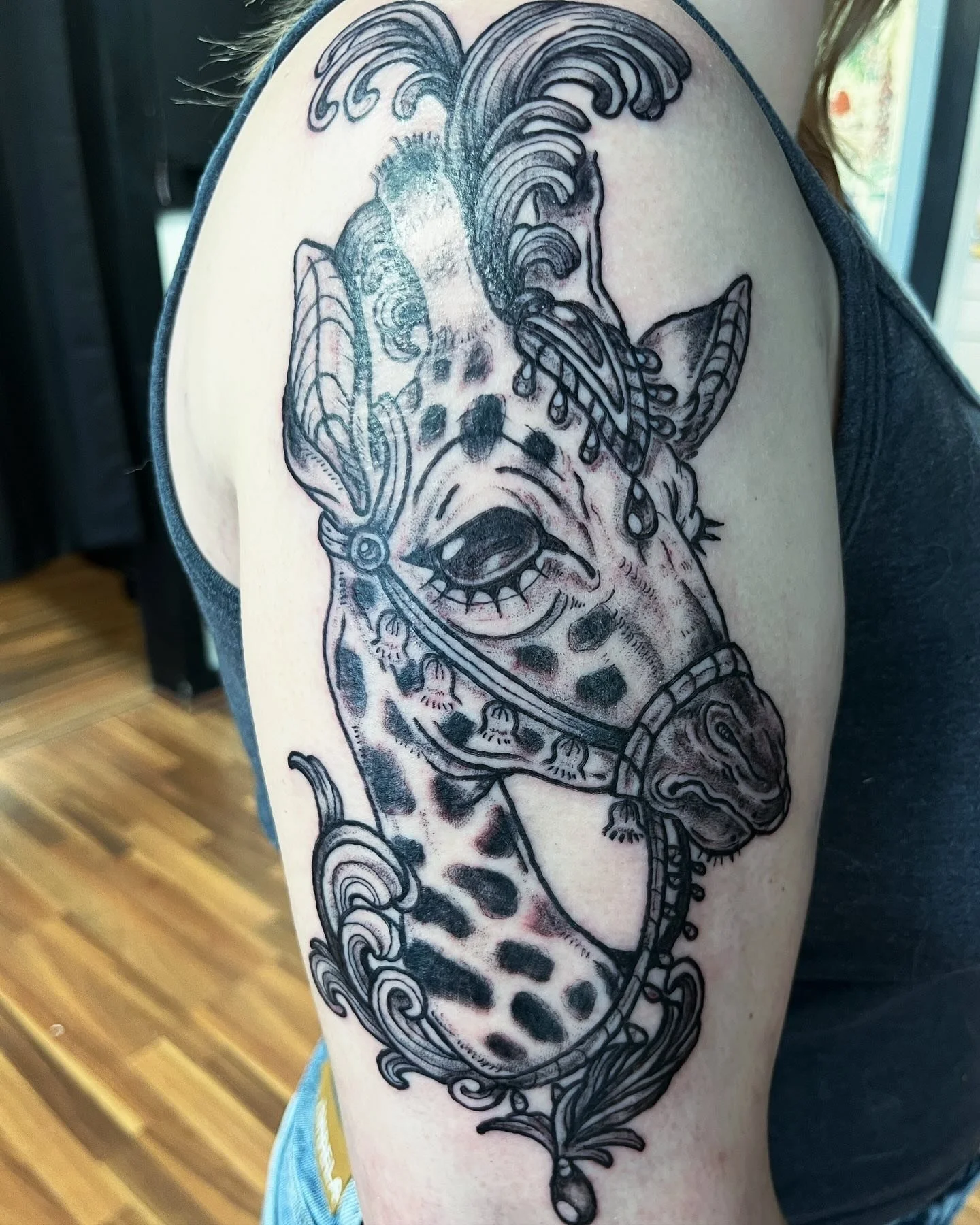 Black and gray tattoo of a cheetah's face and body on a person's upper arm and shoulder, with swirling decorative elements.