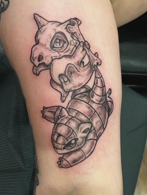 Black outline tattoo of a stylized dragon with a dog skull head, on a person's leg.