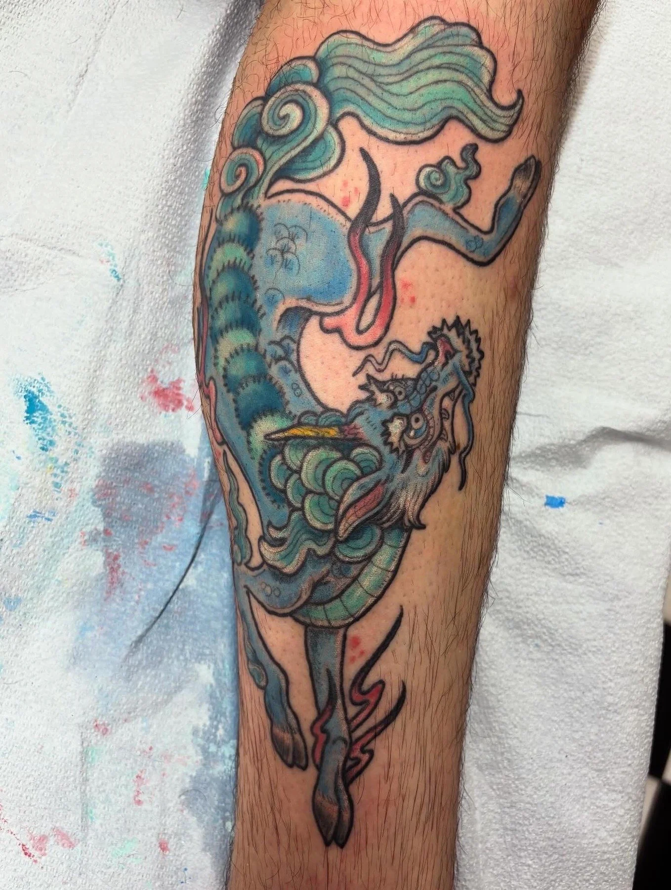Colorful tattoo of a mermaid with flowing hair and a fish tail on a person's arm.
