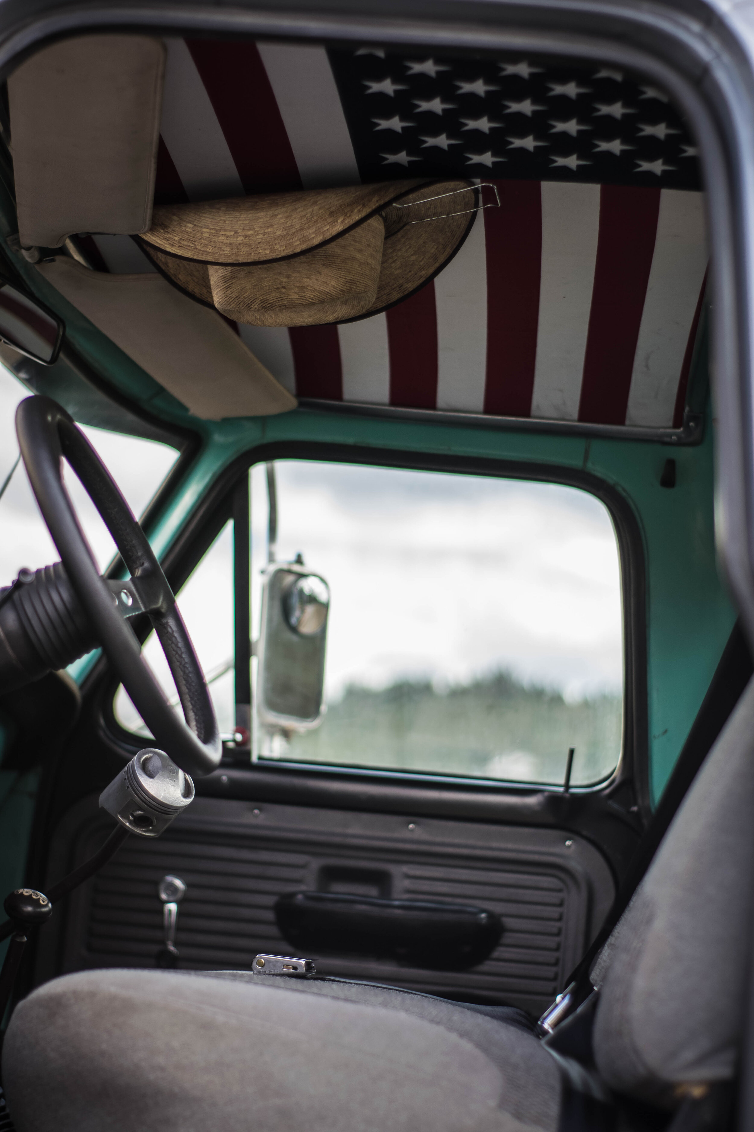  Some of my signature touches include custom interior finishes, like one off door panels and headliners. Snuggled up next to old glory is one of the two things every farm truck needs, a holder for your cowboy hat.  