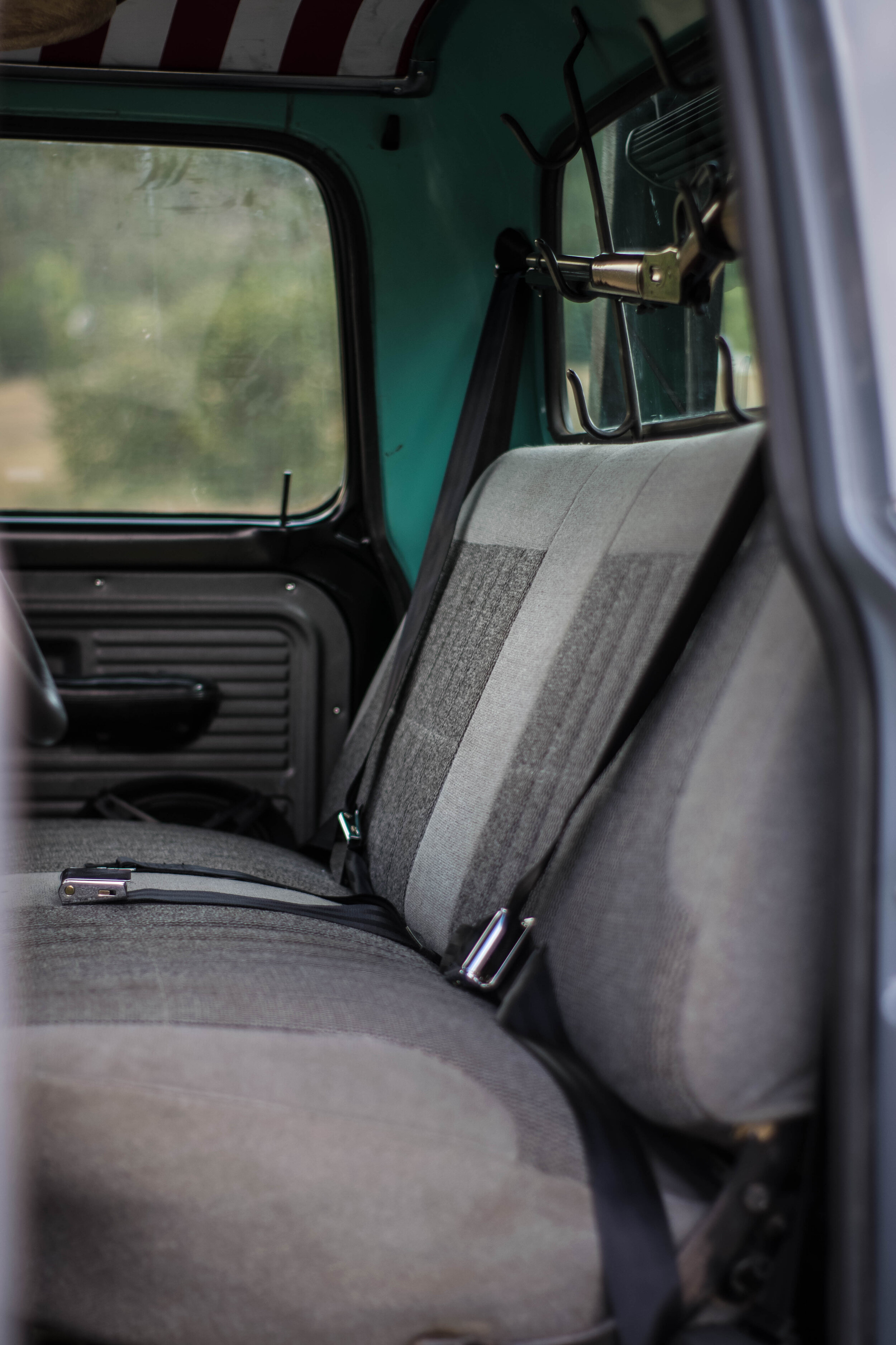  A 90s F150 bench seat adds some extra support, along with a bit of refinement. The grey twill fabric was perfect for the paint color, and far more comfortable than vinyl, especially on hot summer days. A complete set of three point seat belts from R