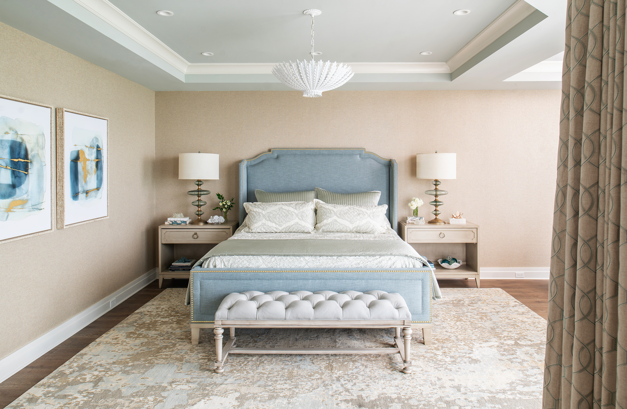 coastal transitional master bedroom with blue bed, tufted ottoman