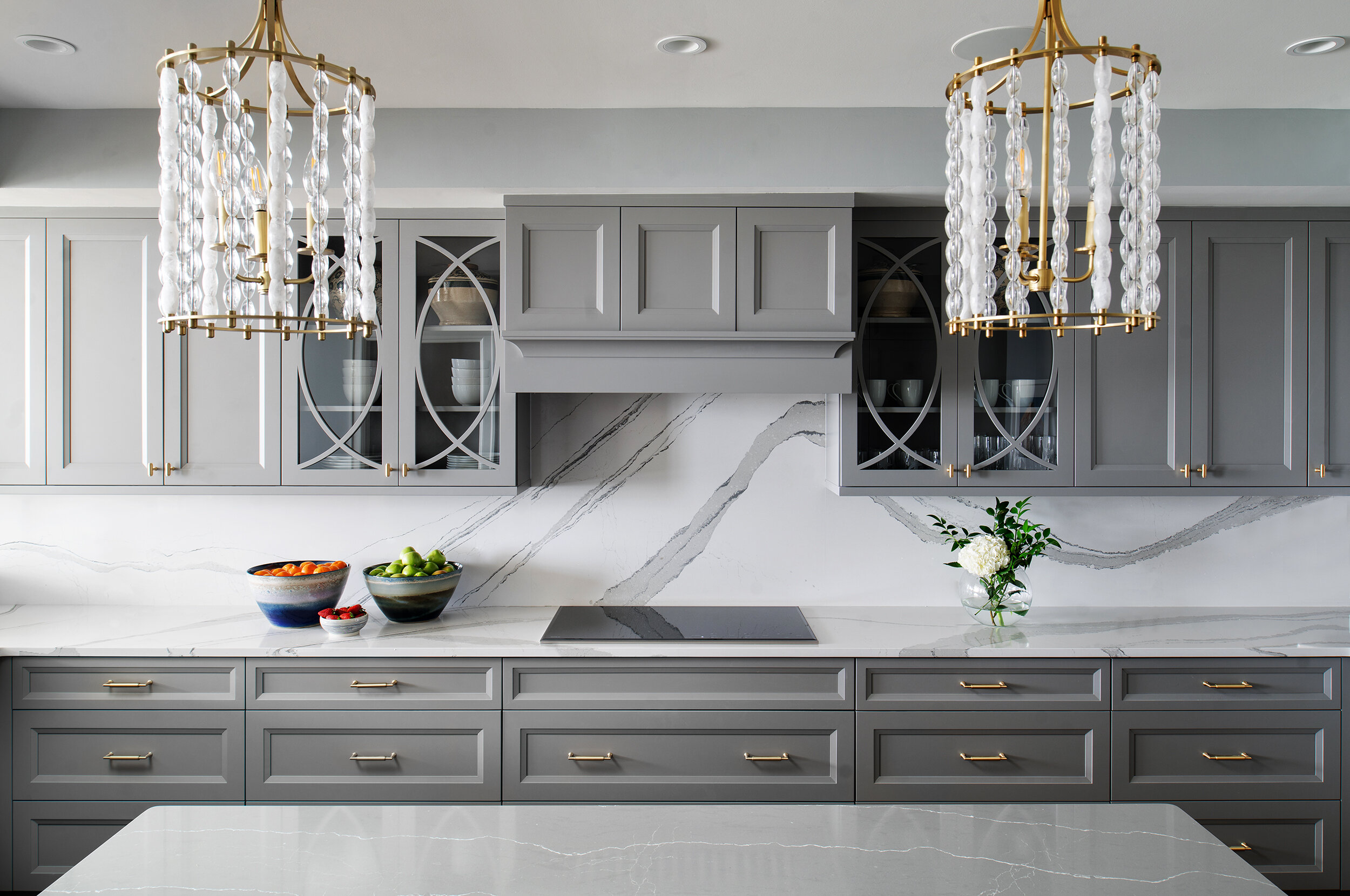 Grey modern kitchen with white marble endless backsplash and gold detail chandelier