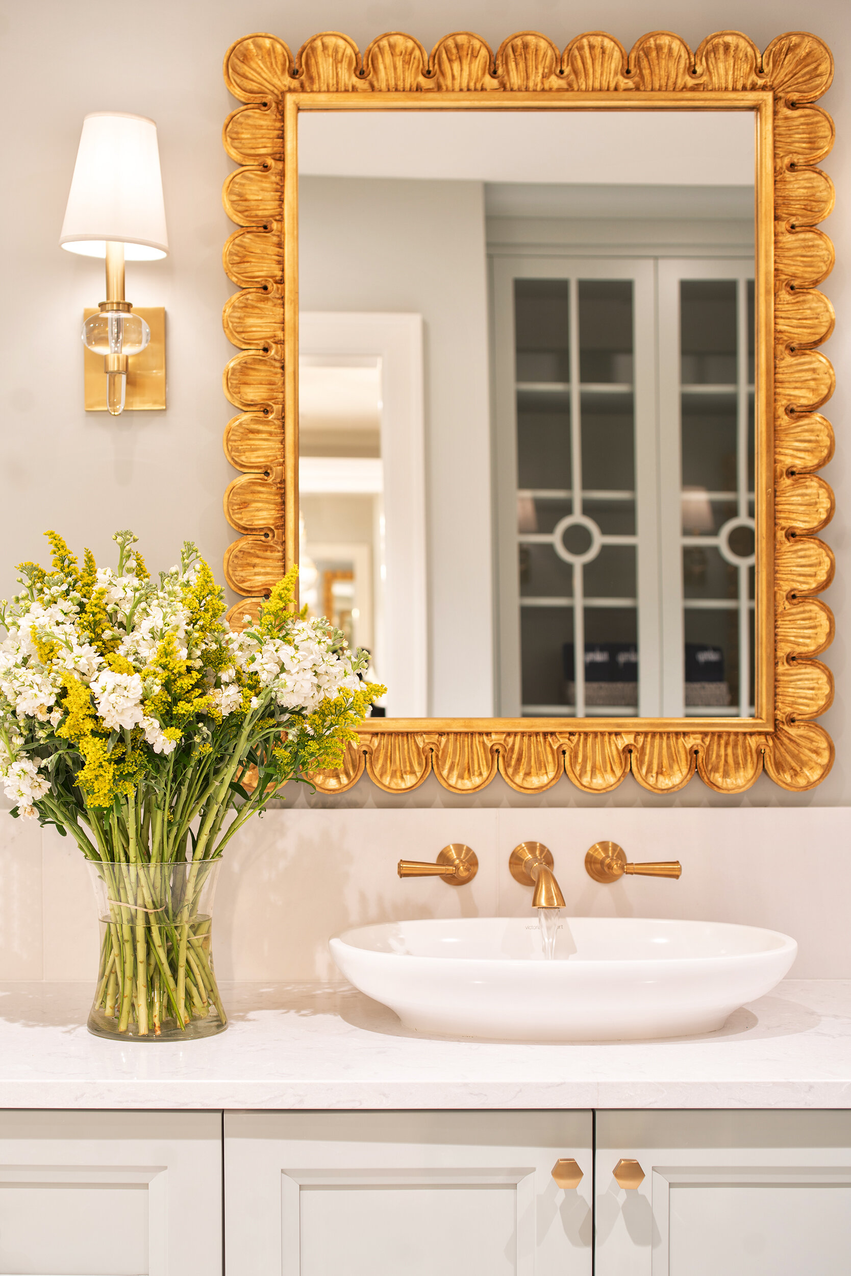 Grey and white bathroom with gold mirror and details