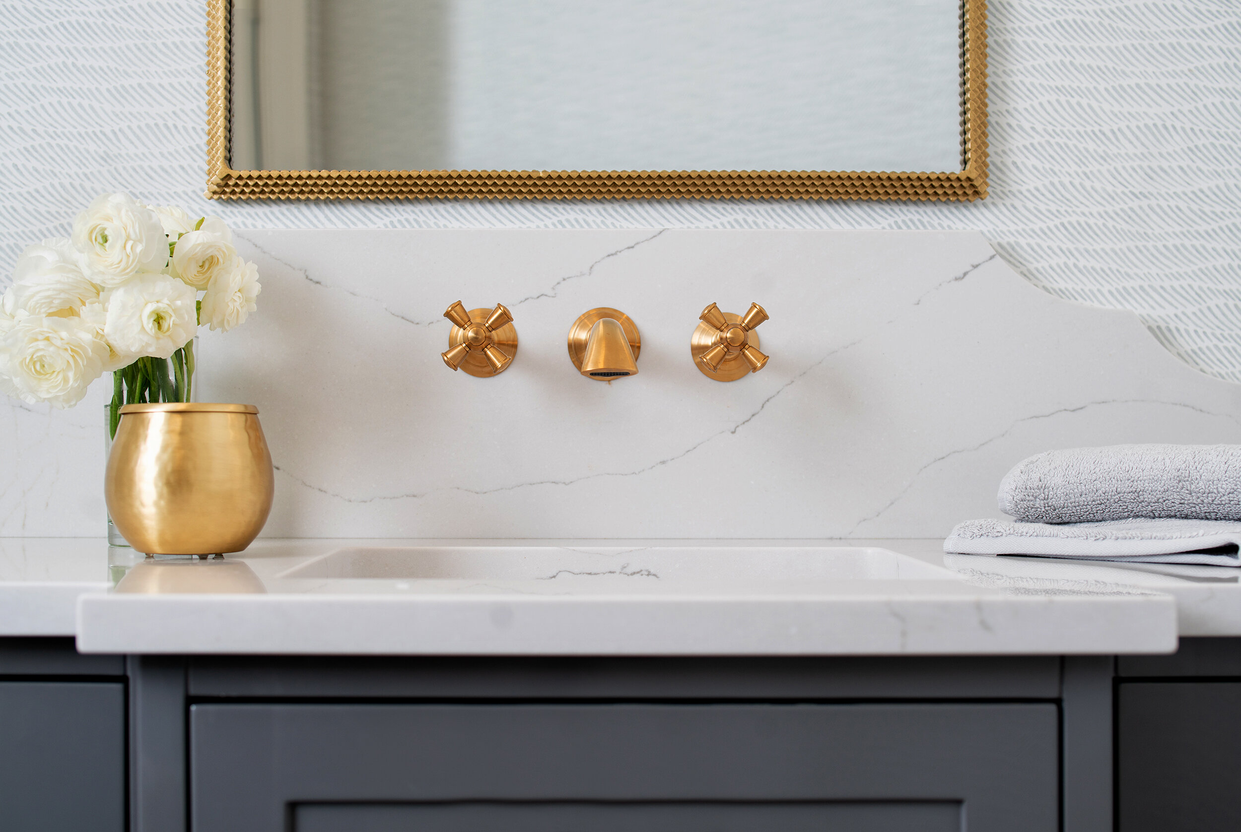 Simple white bathroom with grey cabinets and gold mirror fixtures