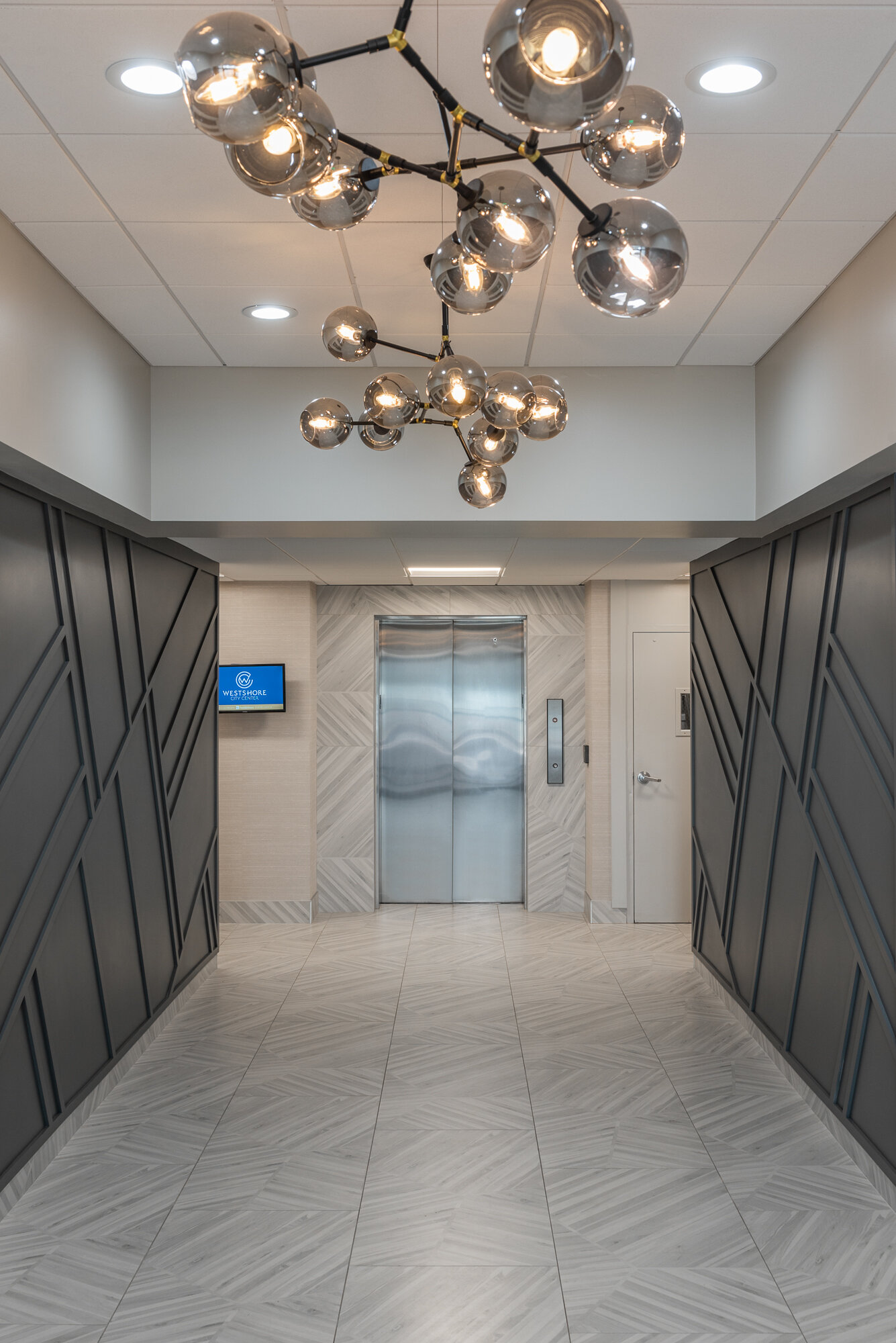 Office lobby big grey wood accent wall and silver ball chandelier