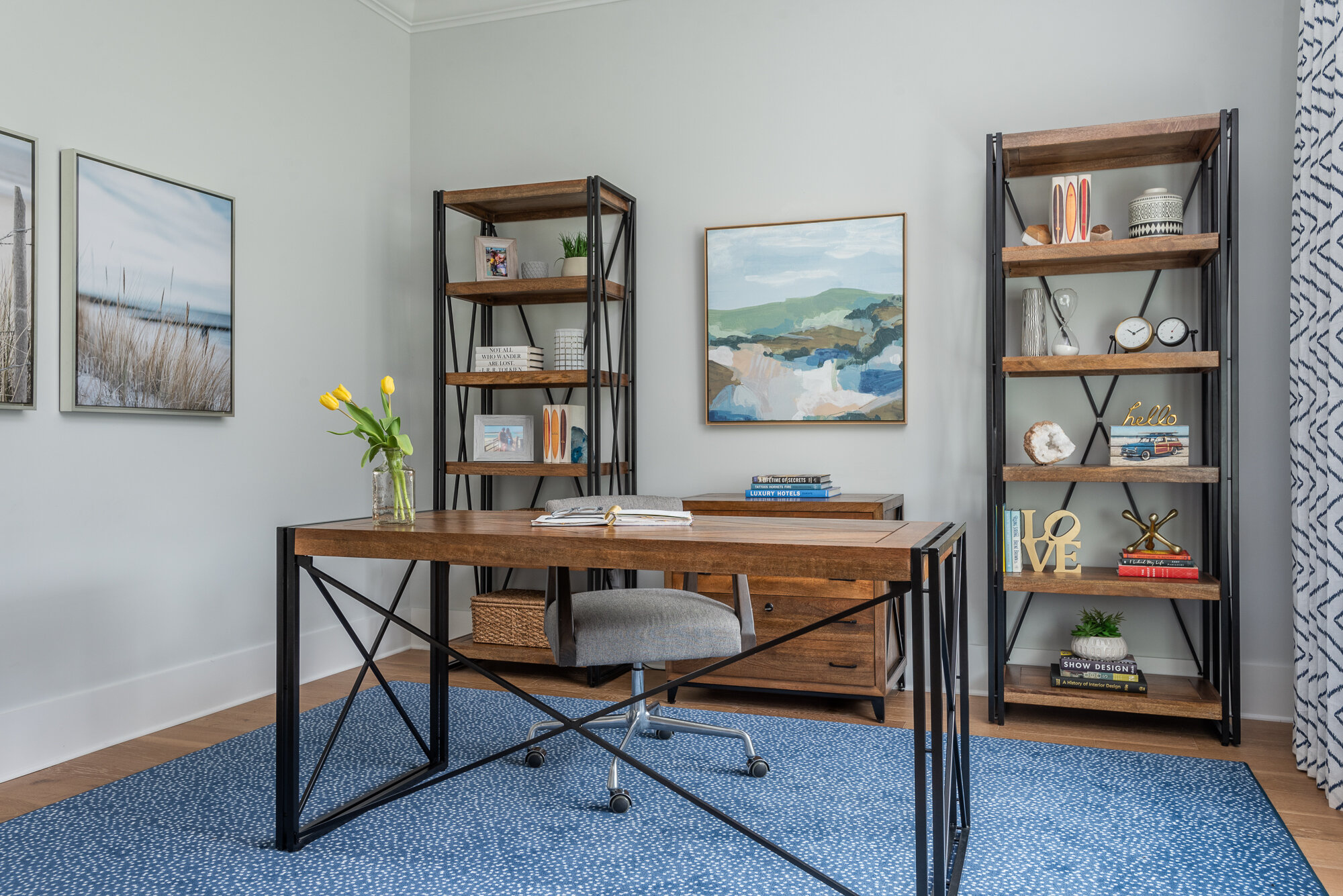 Office with wood and black metal desk and shelves and blue and white dotted rug