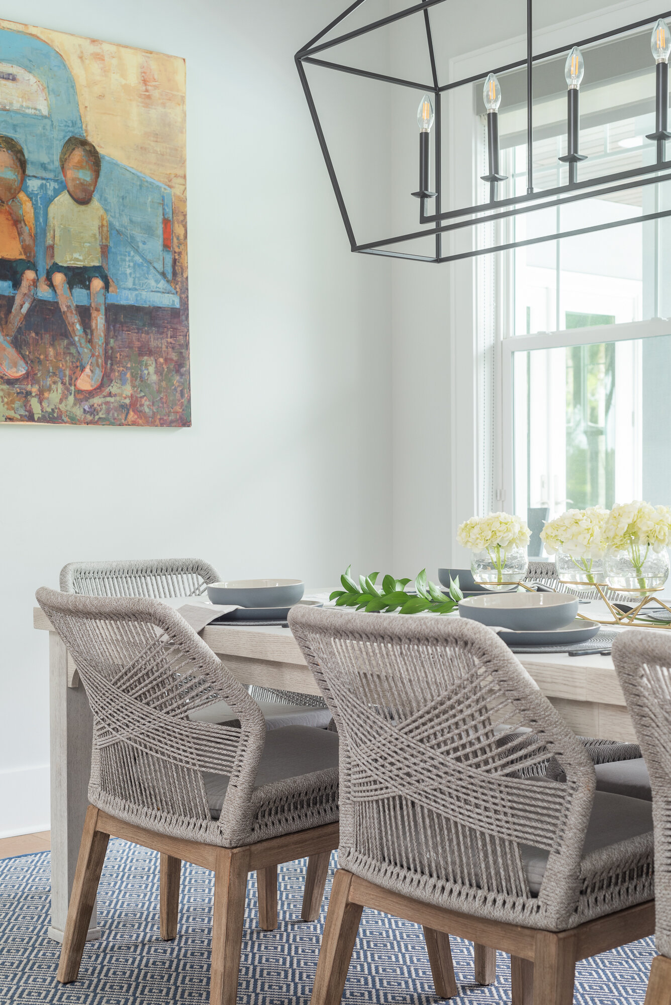 Light brown woven chairs for dining room with black metal chandelier