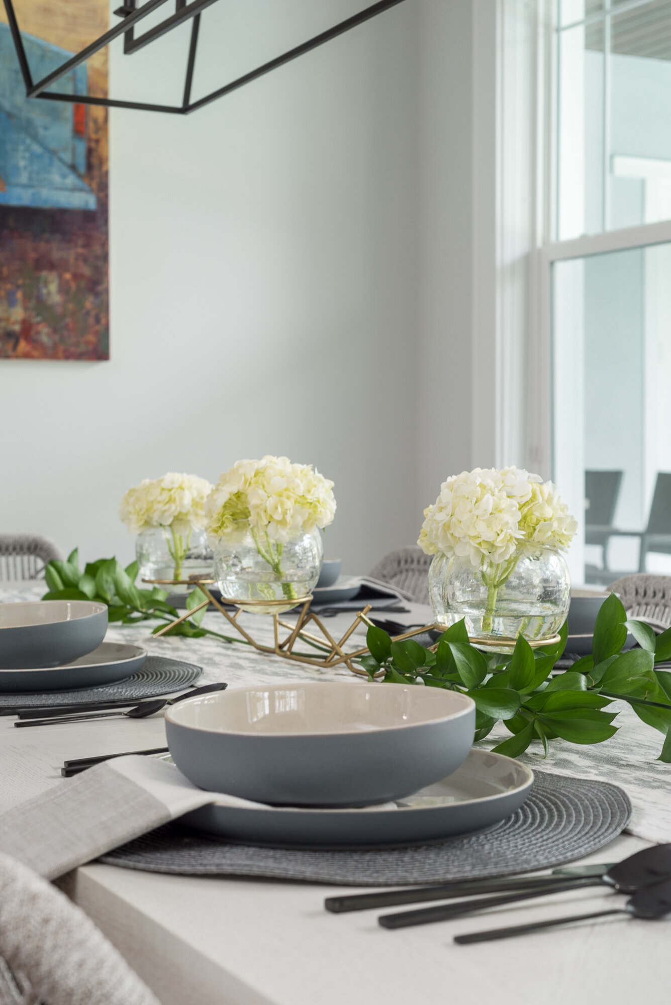 Dining room table scape with white flowers and black silverware 