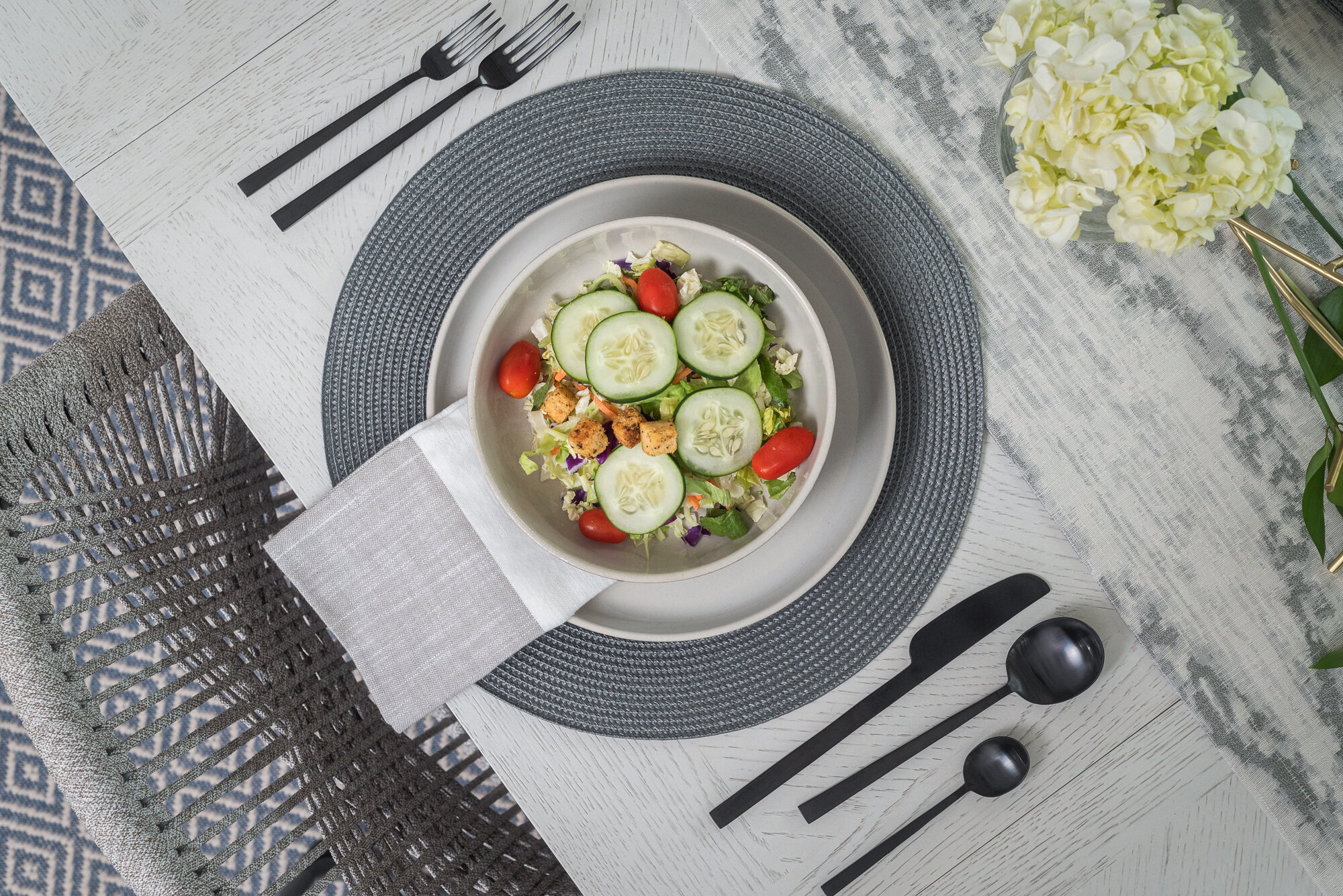 Dining room table scape with white flowers and black silverware 