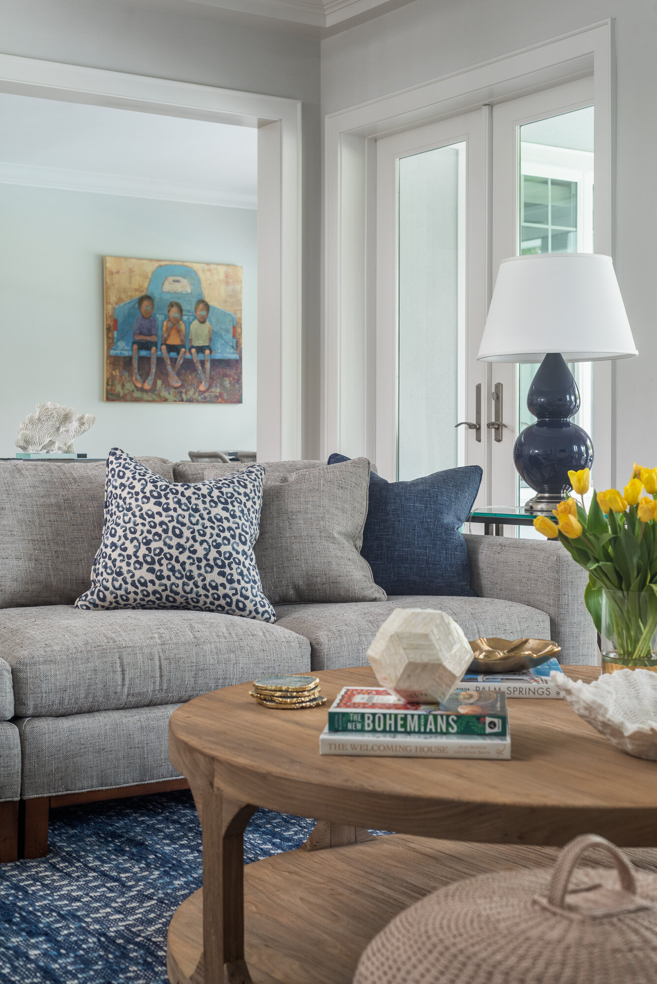 Grey couch, wood coffee table, blue pillow and lamp accents