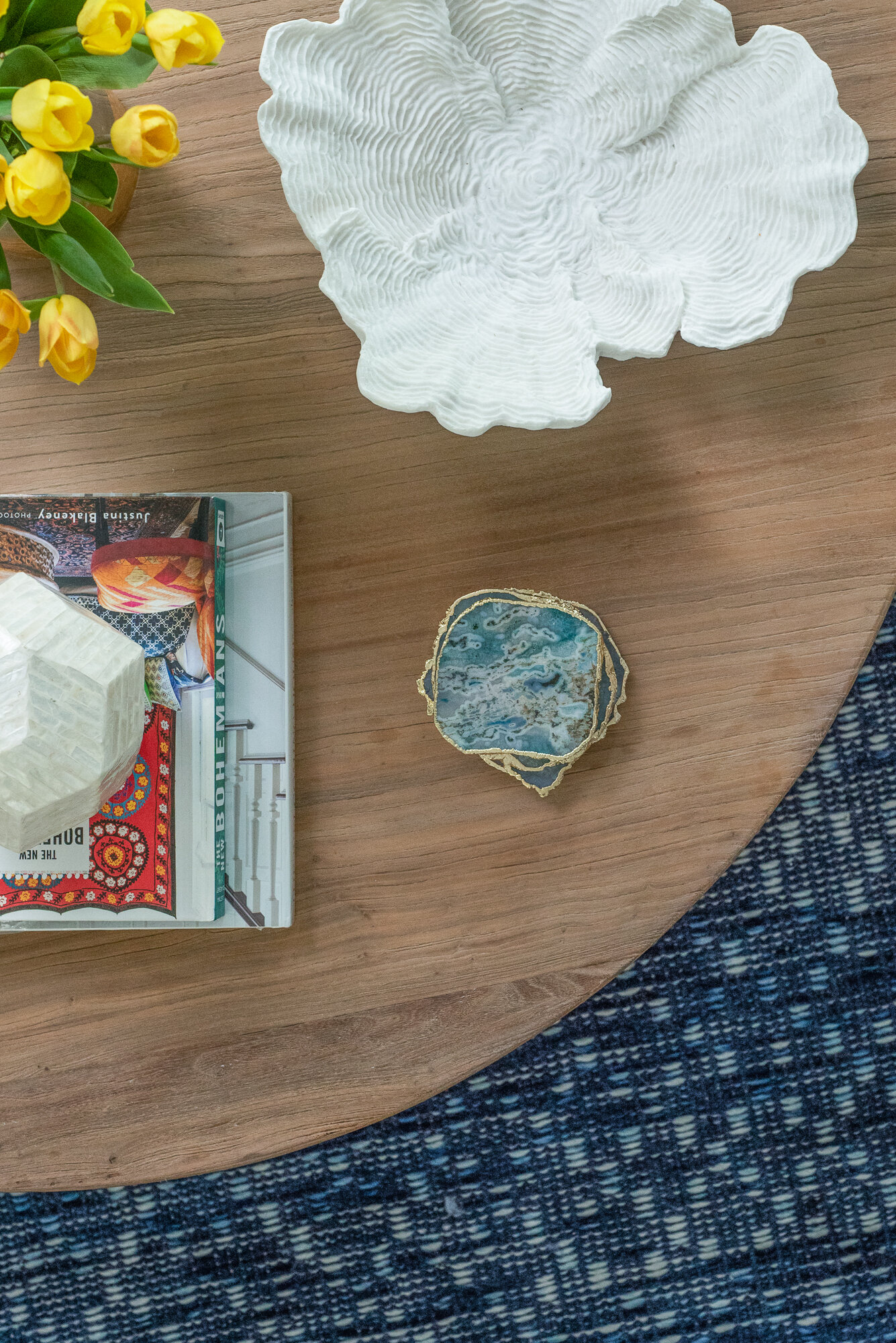 Coffee table details with coasters, white and yellow flowers and blue pattern rug