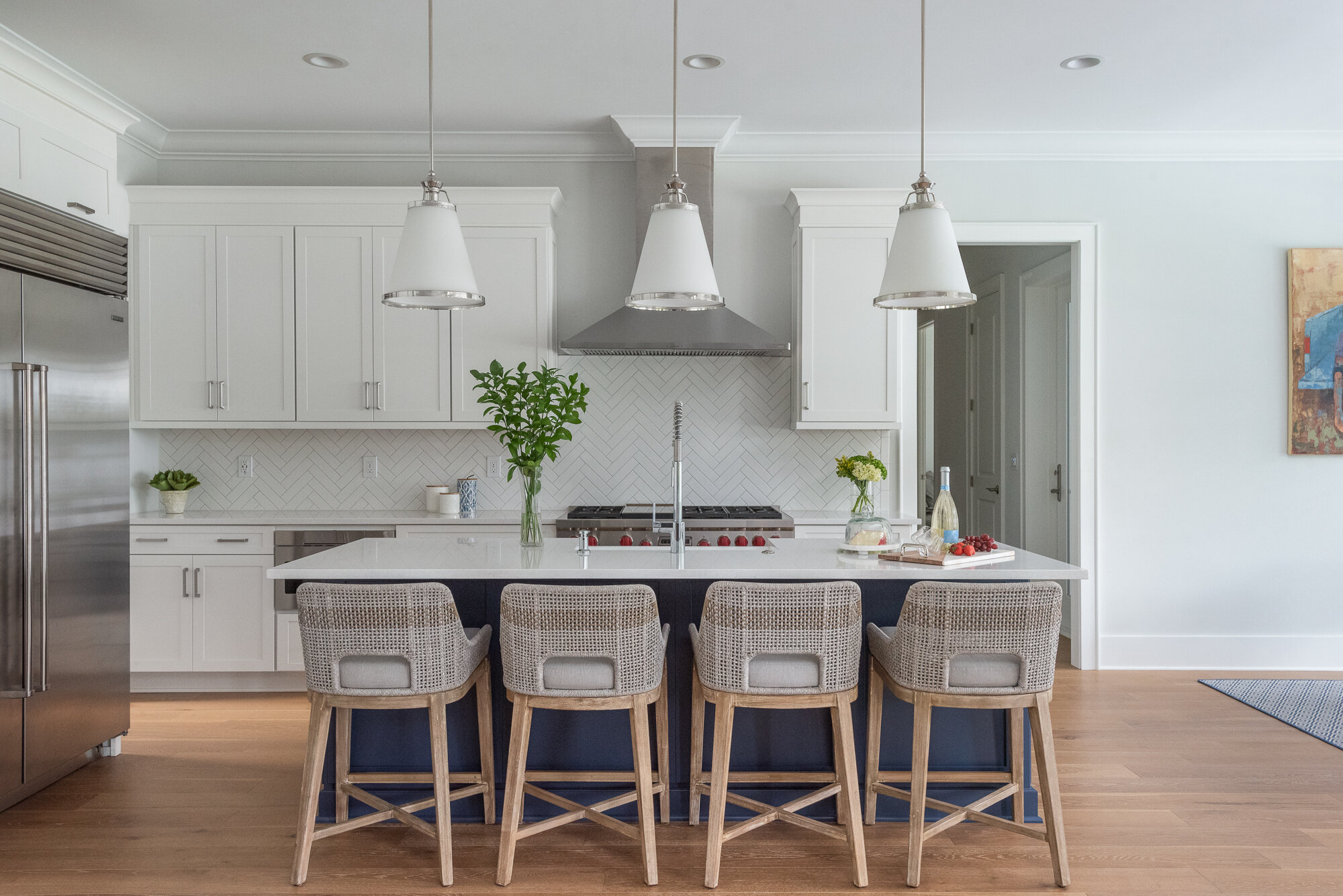 white and grey kitchen with woven bar stools and dark blue island
