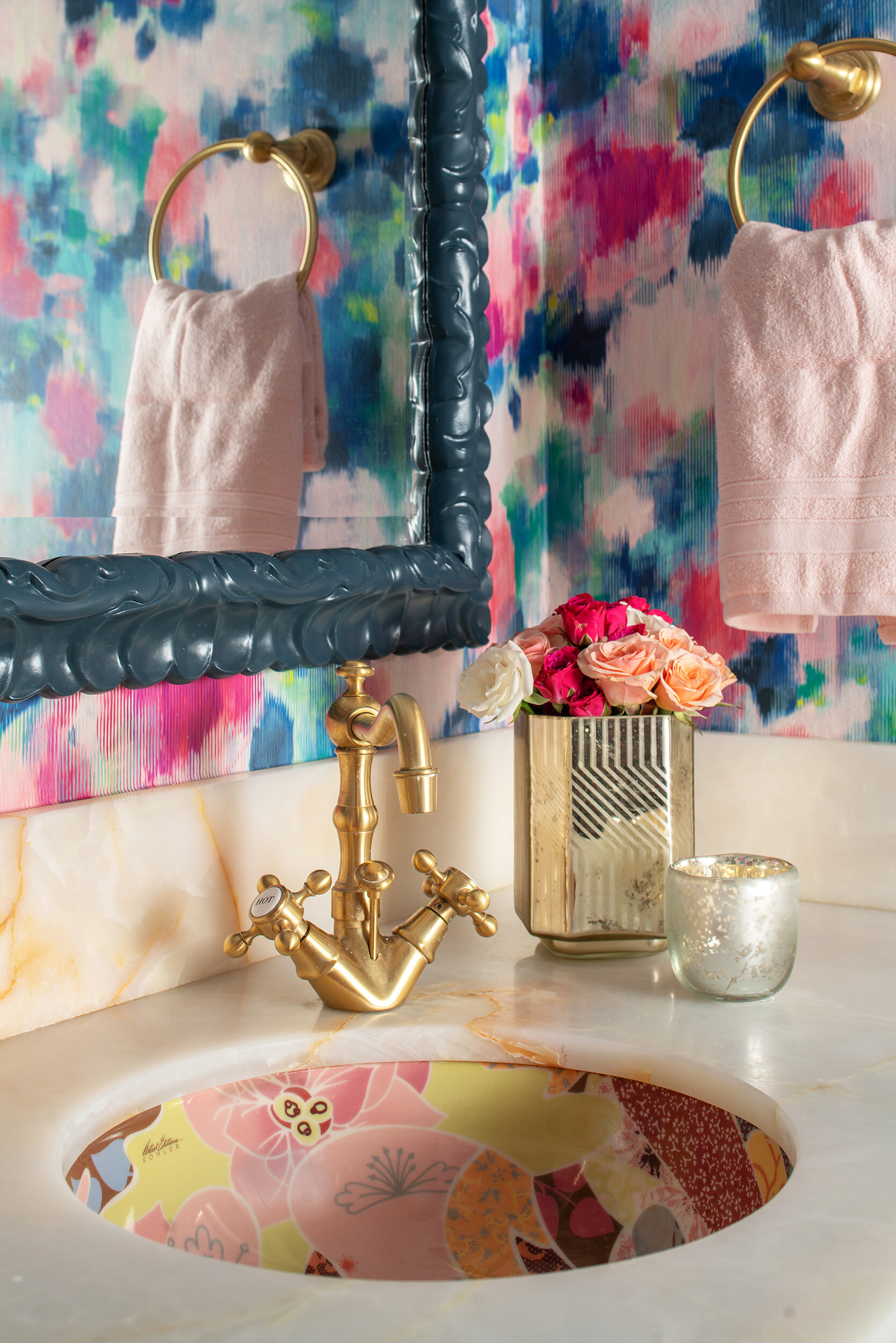Bathroom colorful wallpaper with blue grey cabinets and gold fixtures