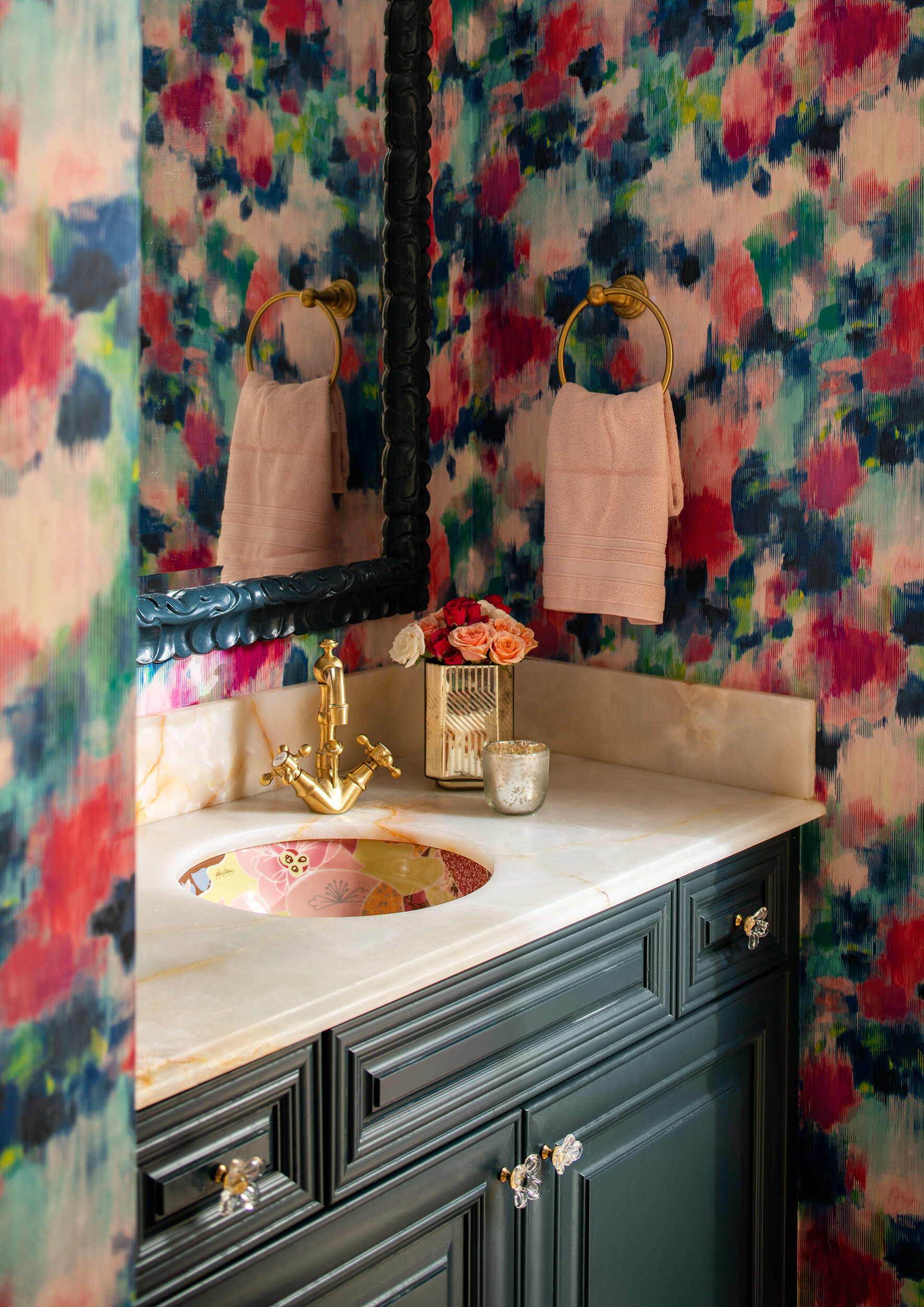 Bathroom colorful wallpaper with blue grey cabinets and gold fixtures