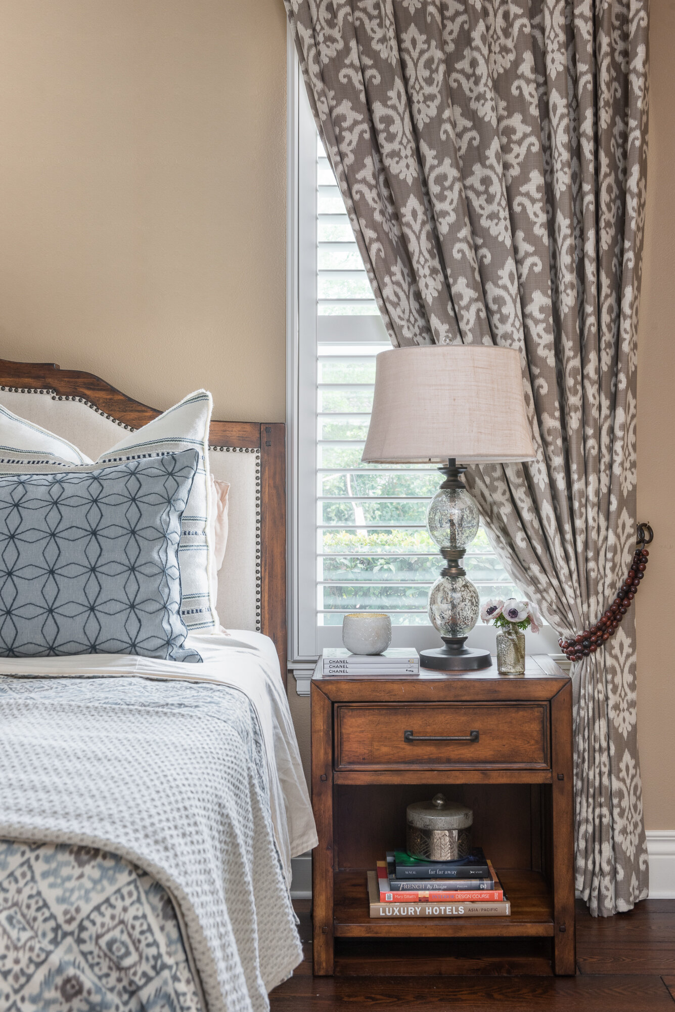 Wood, blue, and cream bedroom with blue printed window treatment curtains