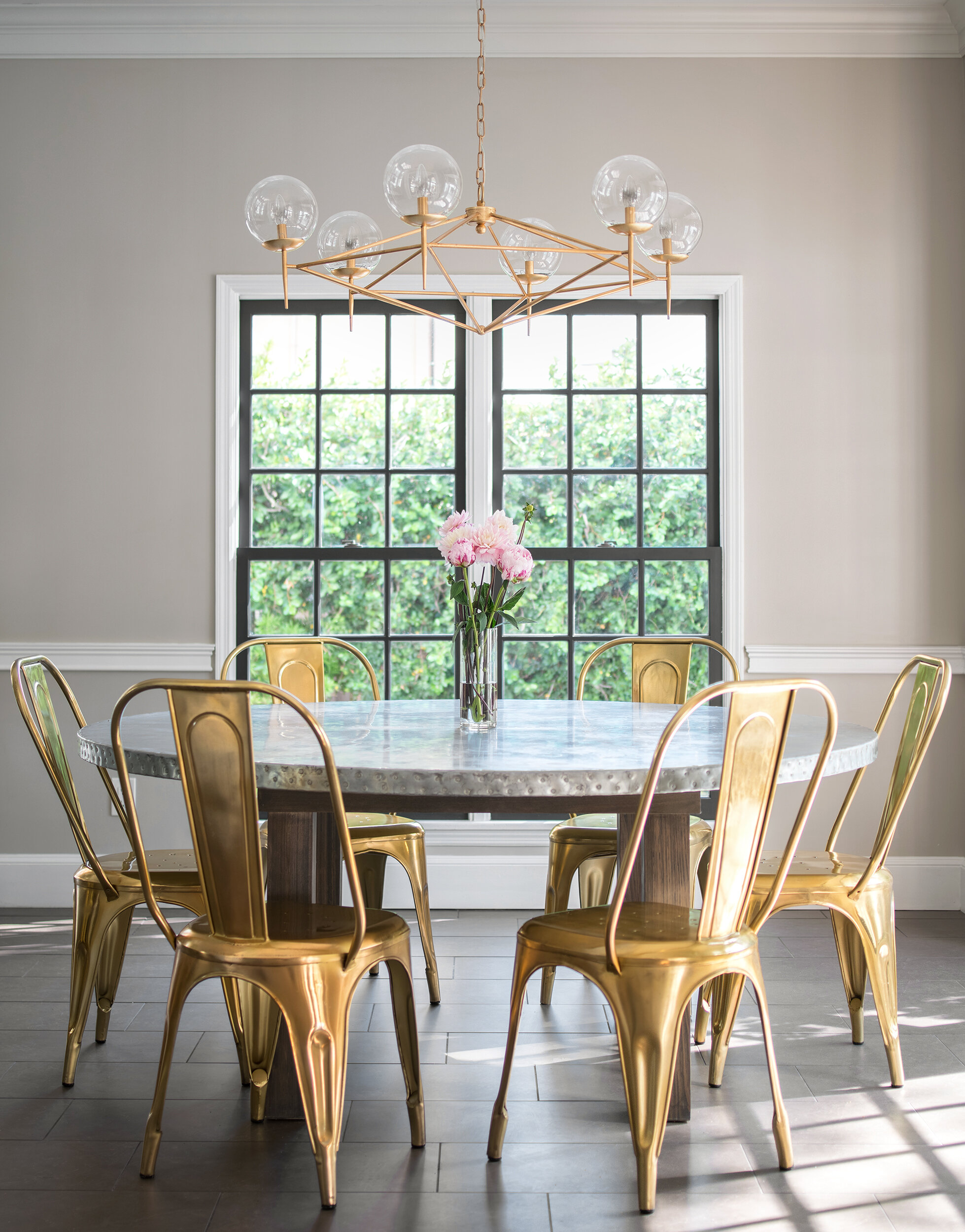 breakfast nook round table with yellow chairs and ball chandelier
