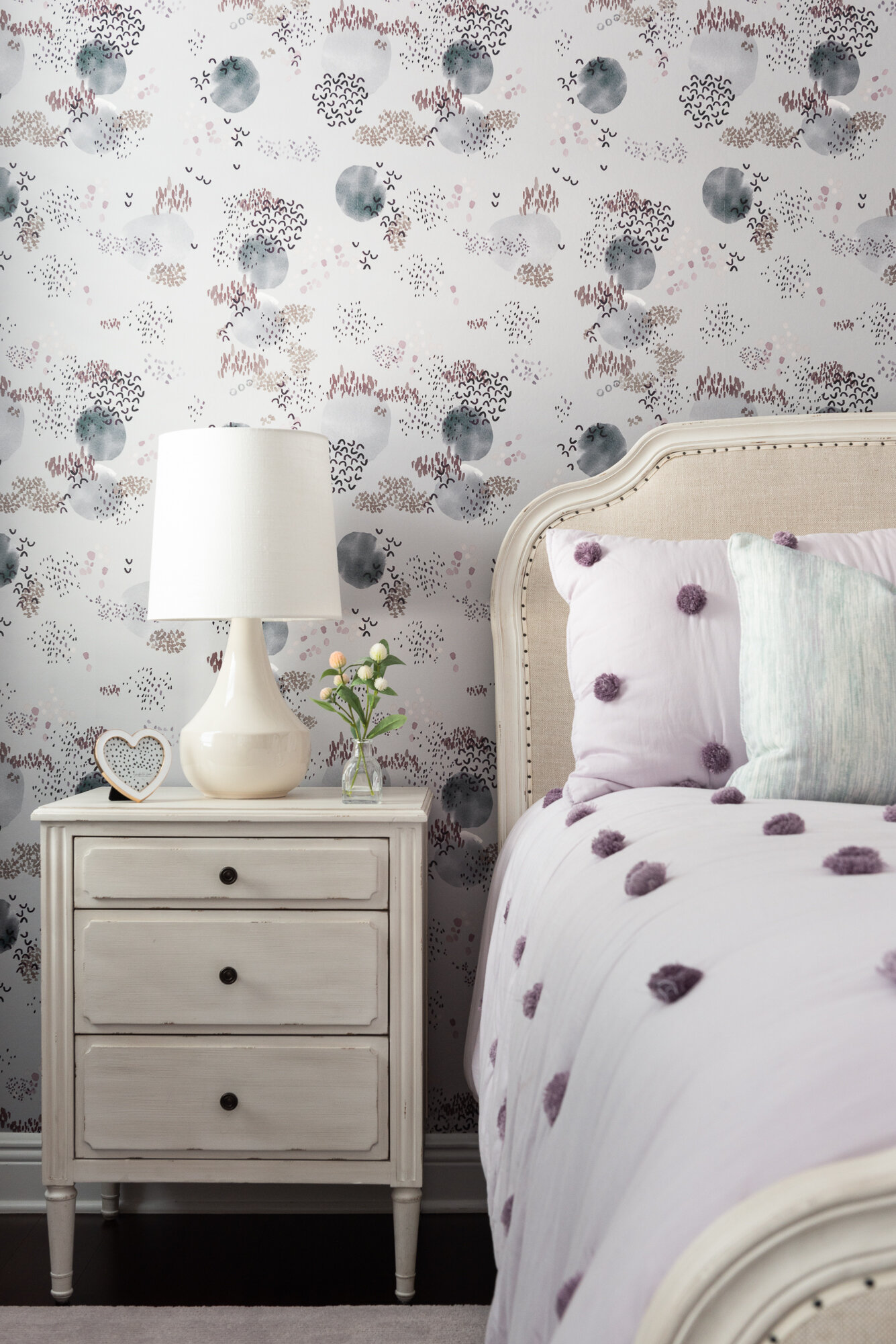 bedroom purple floral wallpaper with white bedside table and comforter