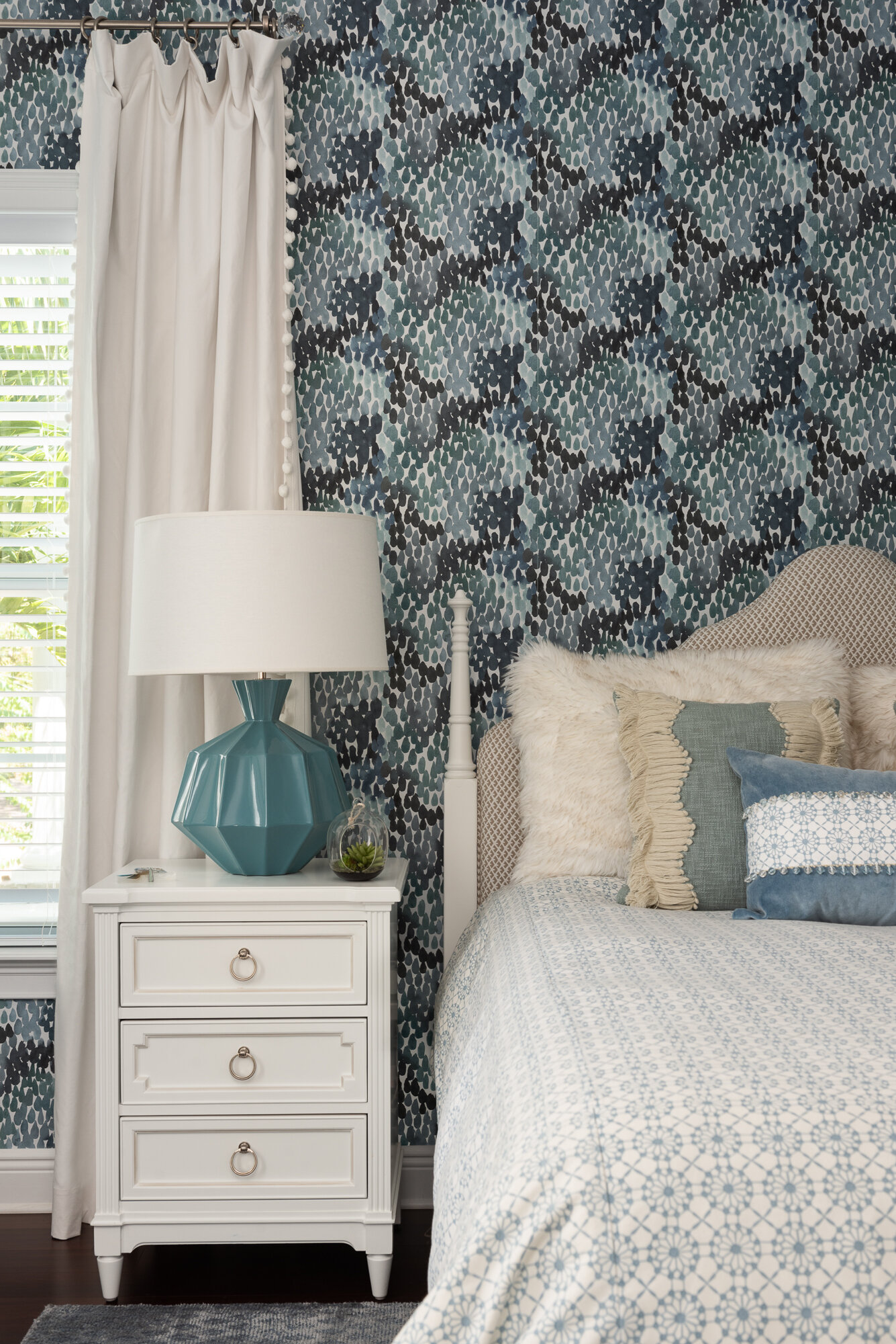 bedroom blue floral wallpaper with white bedside table and comforter 