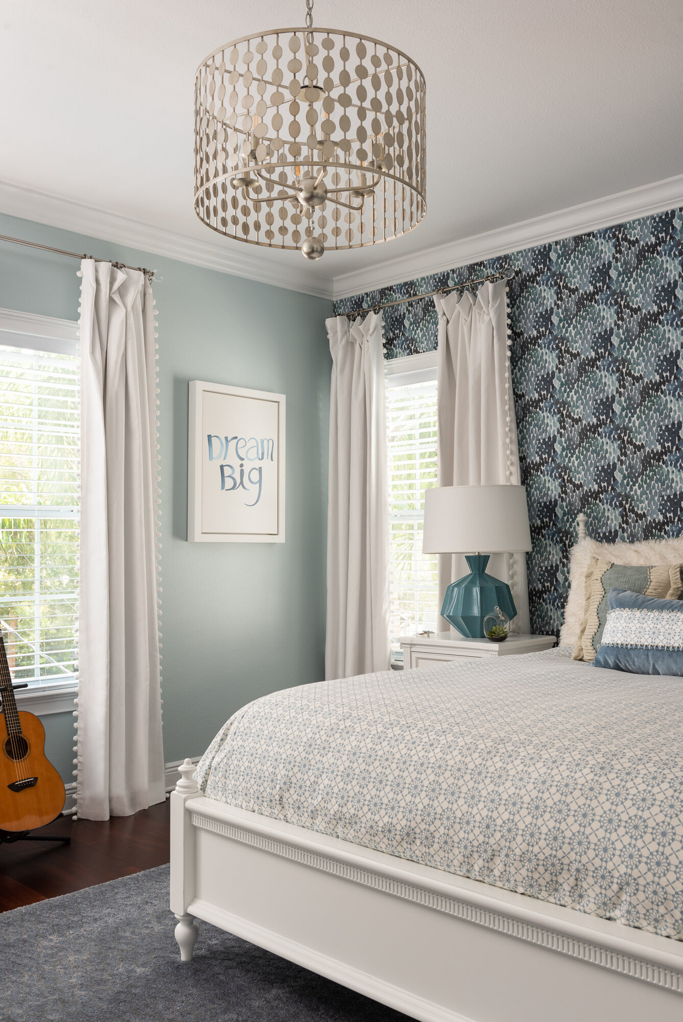 bedroom blue floral wallpaper with white bedside table and comforte