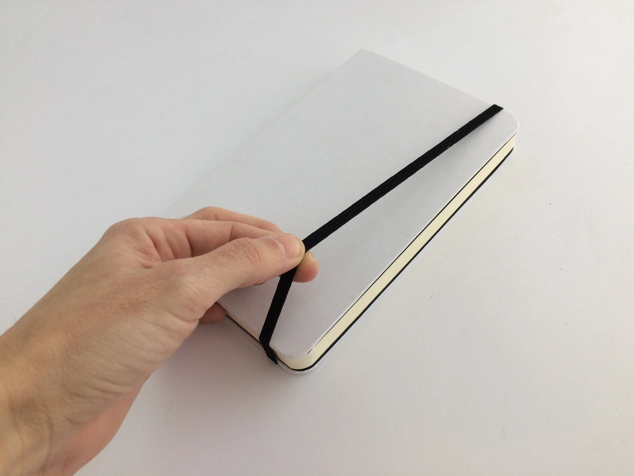Resorte para cerrar la libreta. Disponible en negro o gris claro.