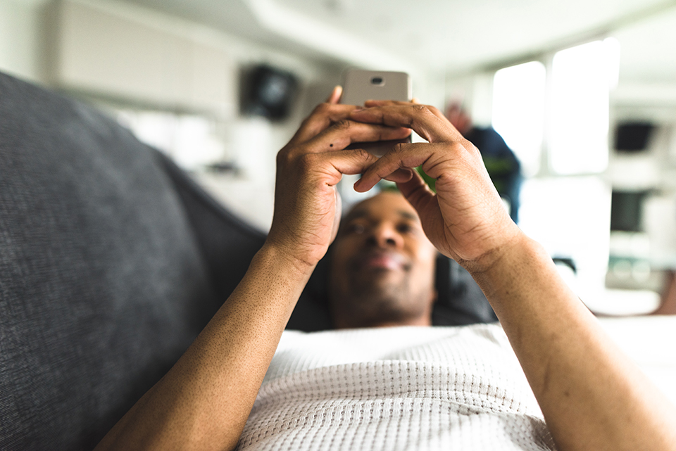 man-relaxing-on-sofa-looking-at-cell-phone.jpg