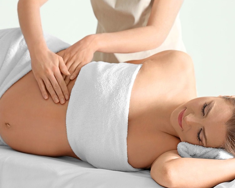 Femme enceinte recevant un massage prénatal du dos, allongée confortablement sur une table de massage.