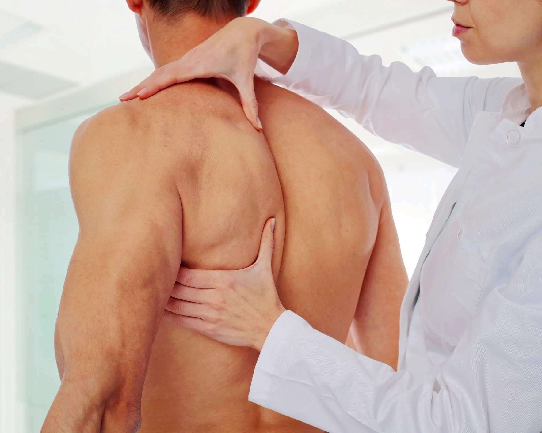 Massage therapist working on a client's shoulder and upper back during a sports massage session in Montreal.